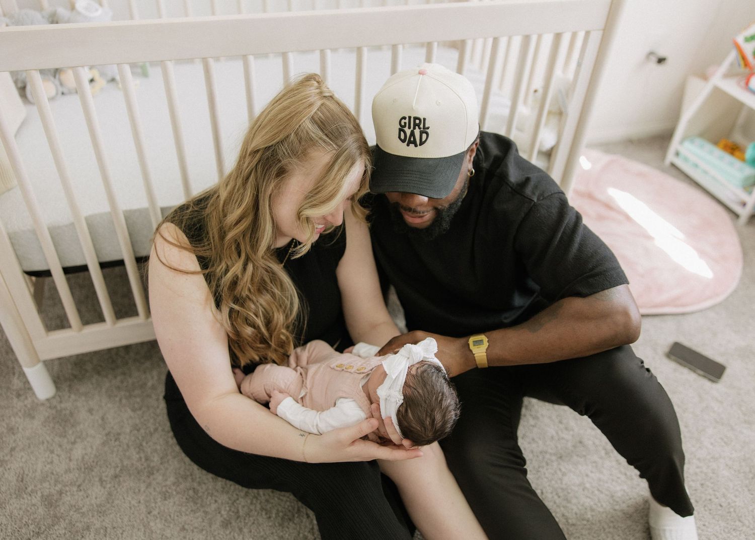 Parents admiring their newborn baby in nursery with white crib.
