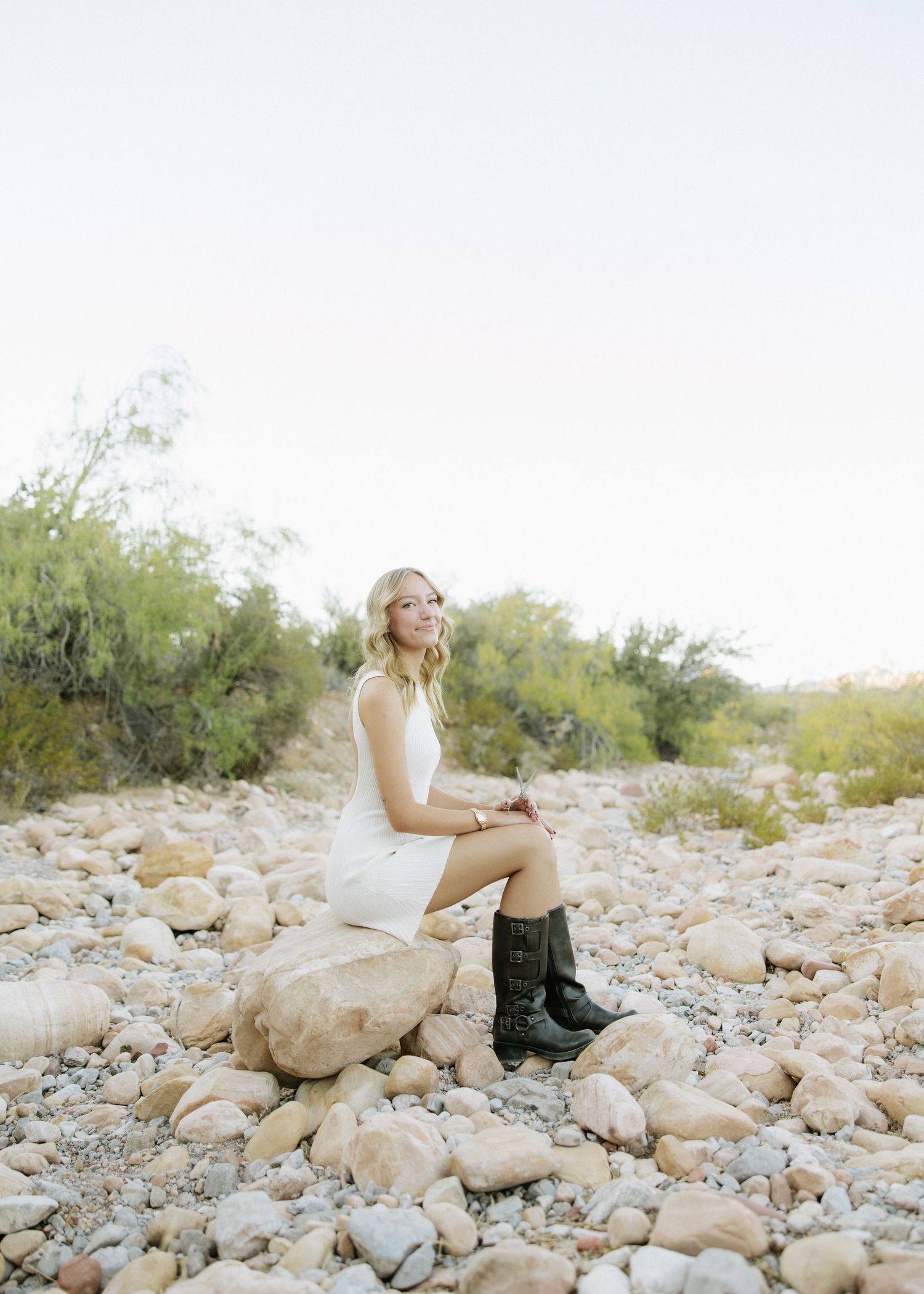 A bridal portrait featuring boots and a wedding dress on rocky desert terrain.