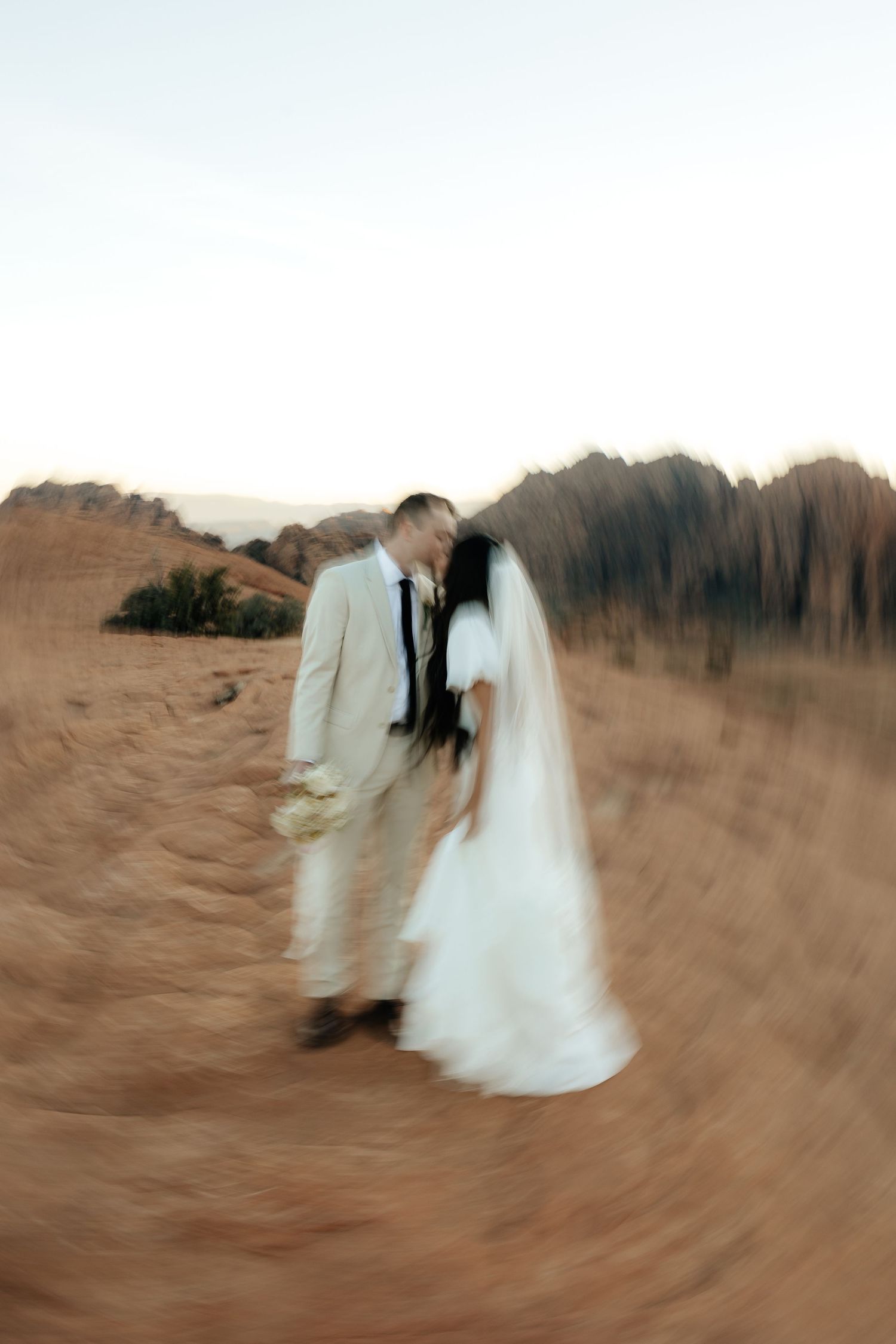 Motion blurred artistic photograph of newlyweds in desert setting.