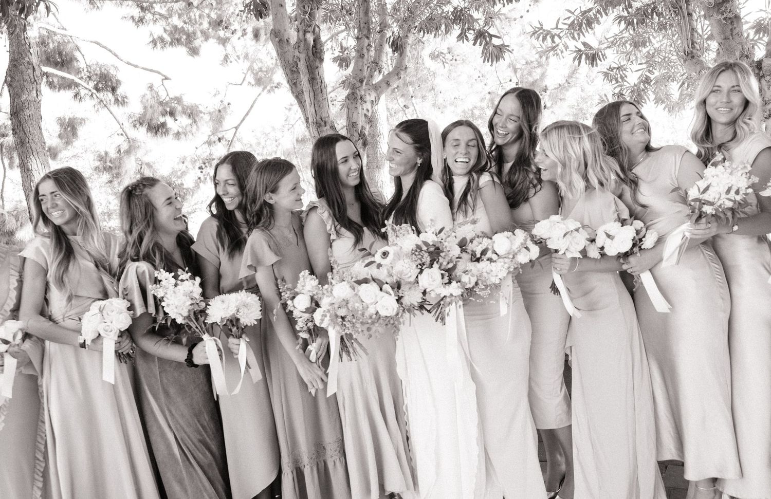 Black and white photo of bridesmaids in flowing dresses holding bouquets.