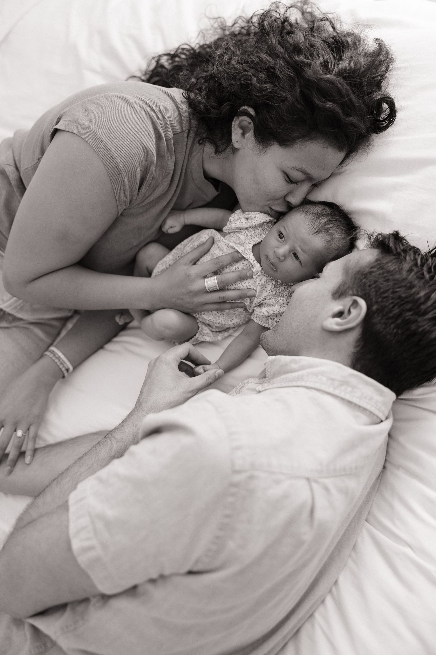 Black and white photo series showing a couple sharing intimate moments while lying in bed together.
