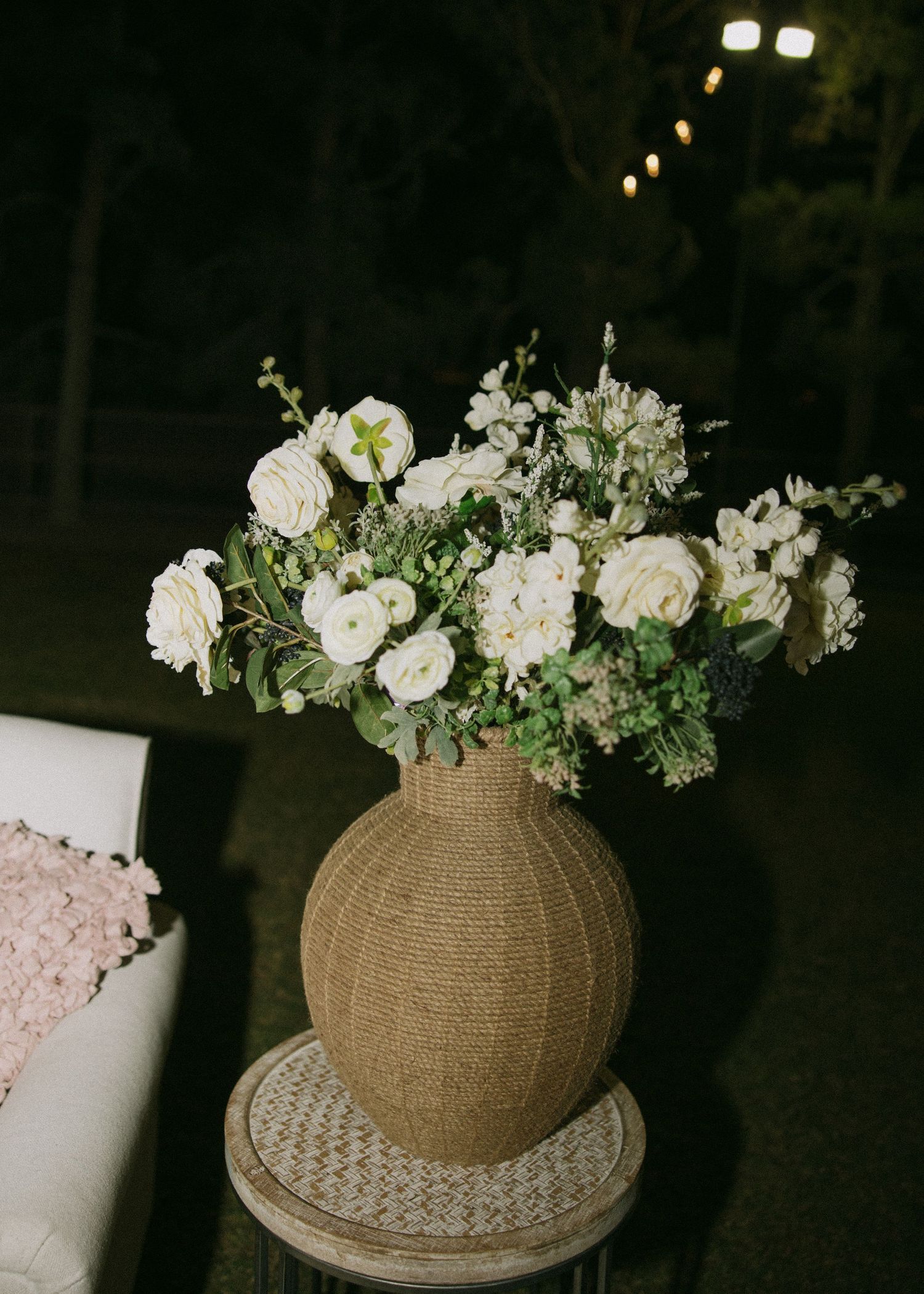 Elegant white floral arrangement in a textured burlap vase with roses and mixed blooms.