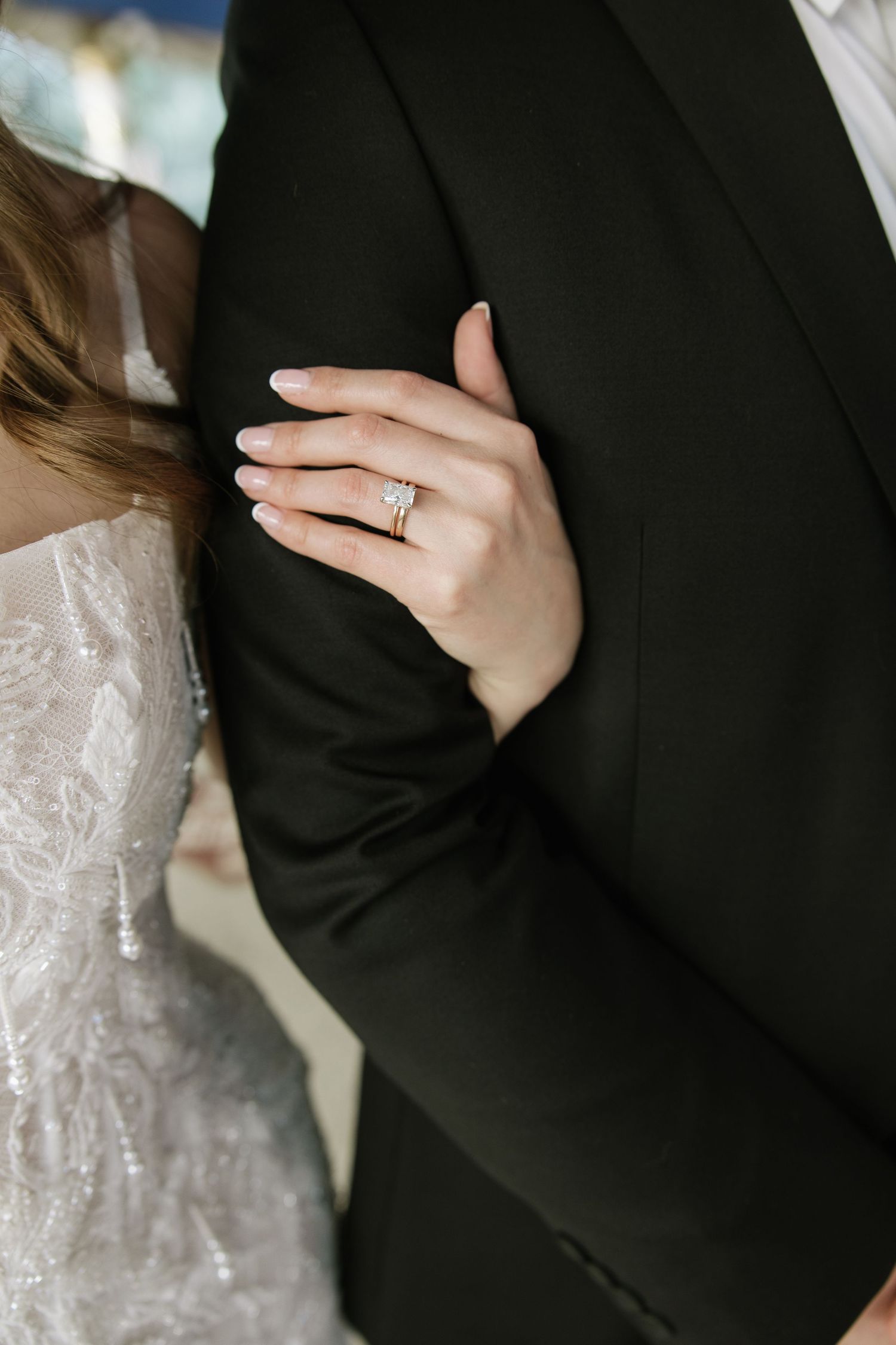 Close-up details of a wedding couple showing hands, rings, and formal attire in black and white tones.
