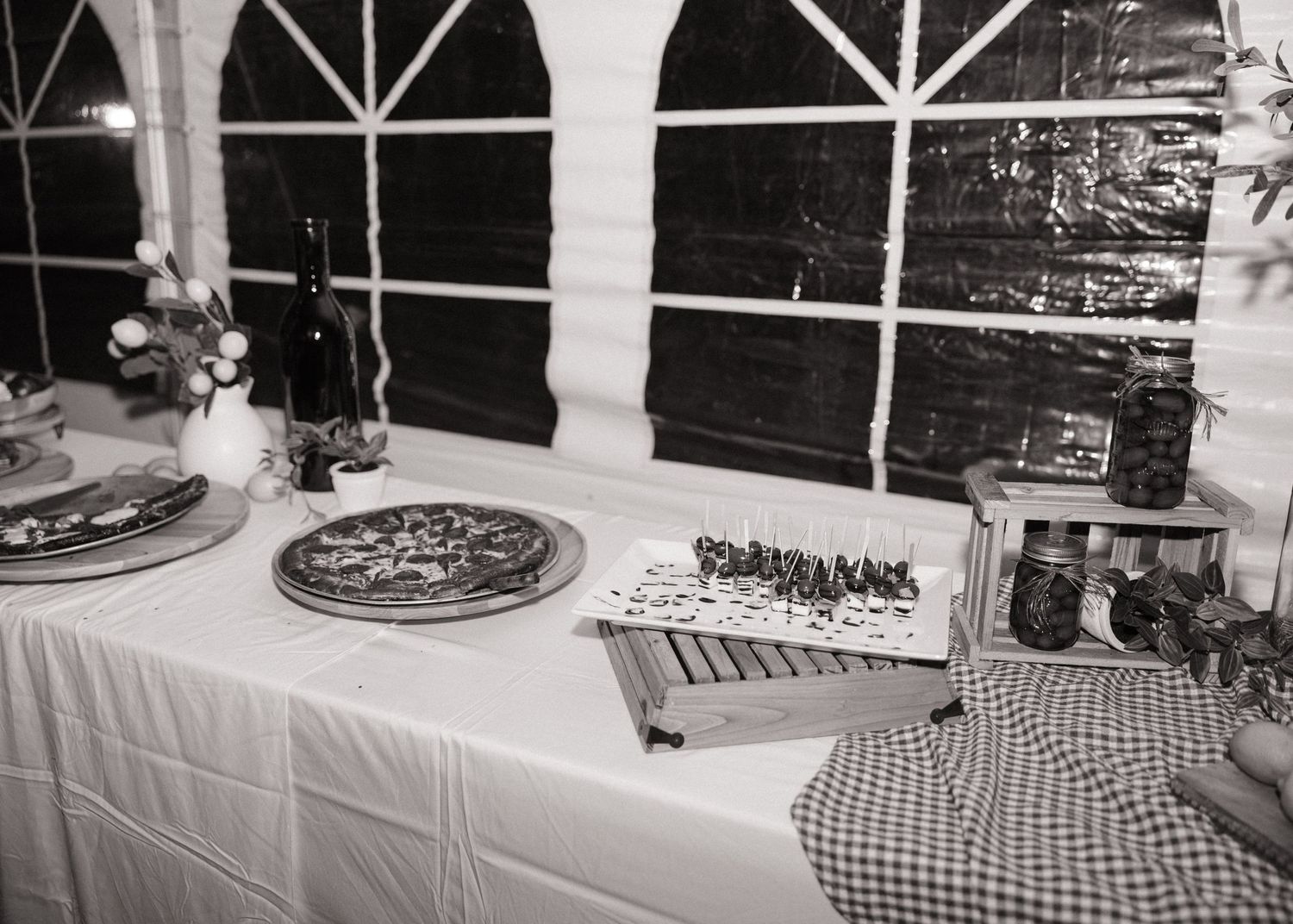 Black and white photo of a dessert table with cakes and treats at a wedding reception.