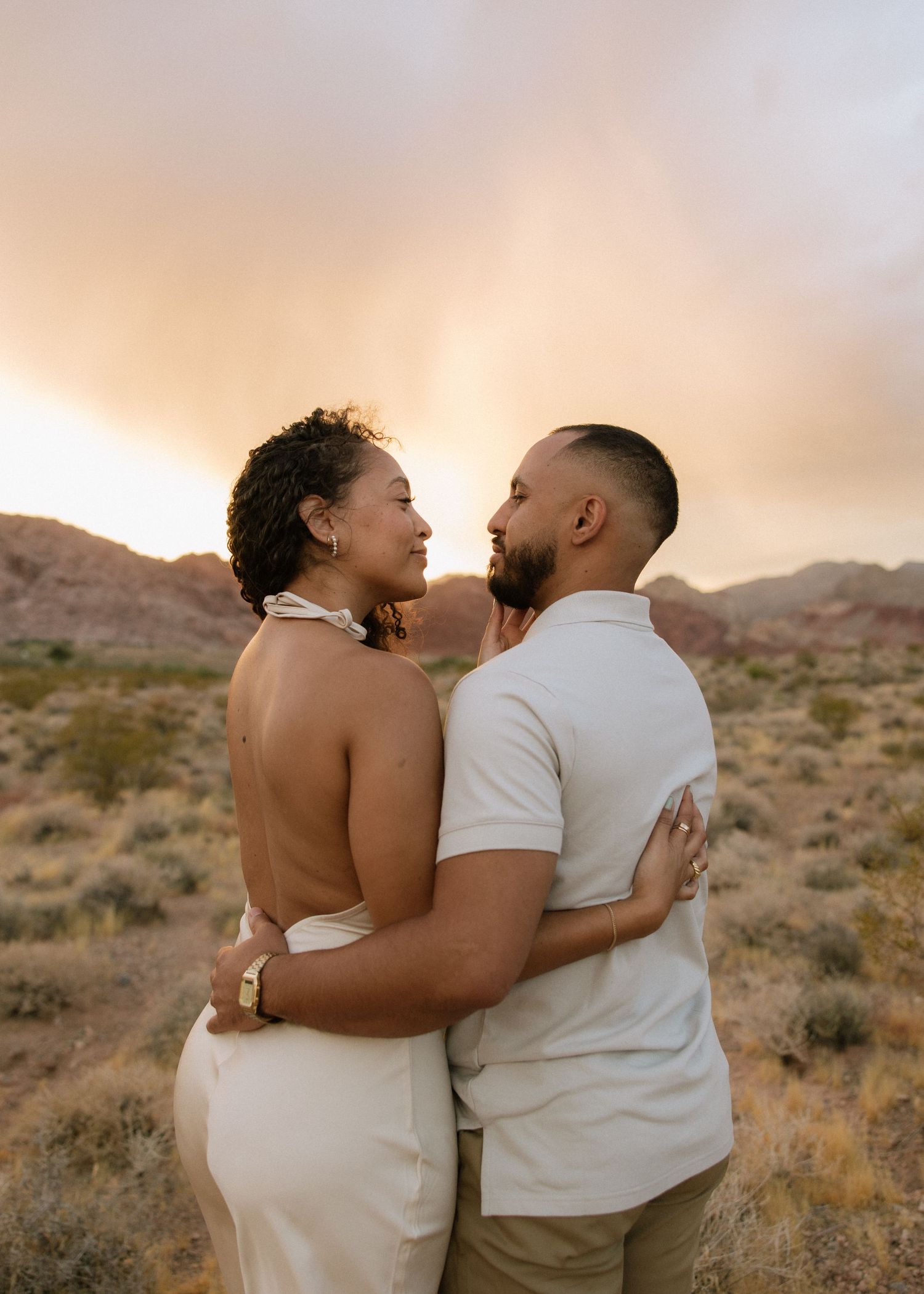 An intimate desert portrait of a couple laughing together at golden hour.