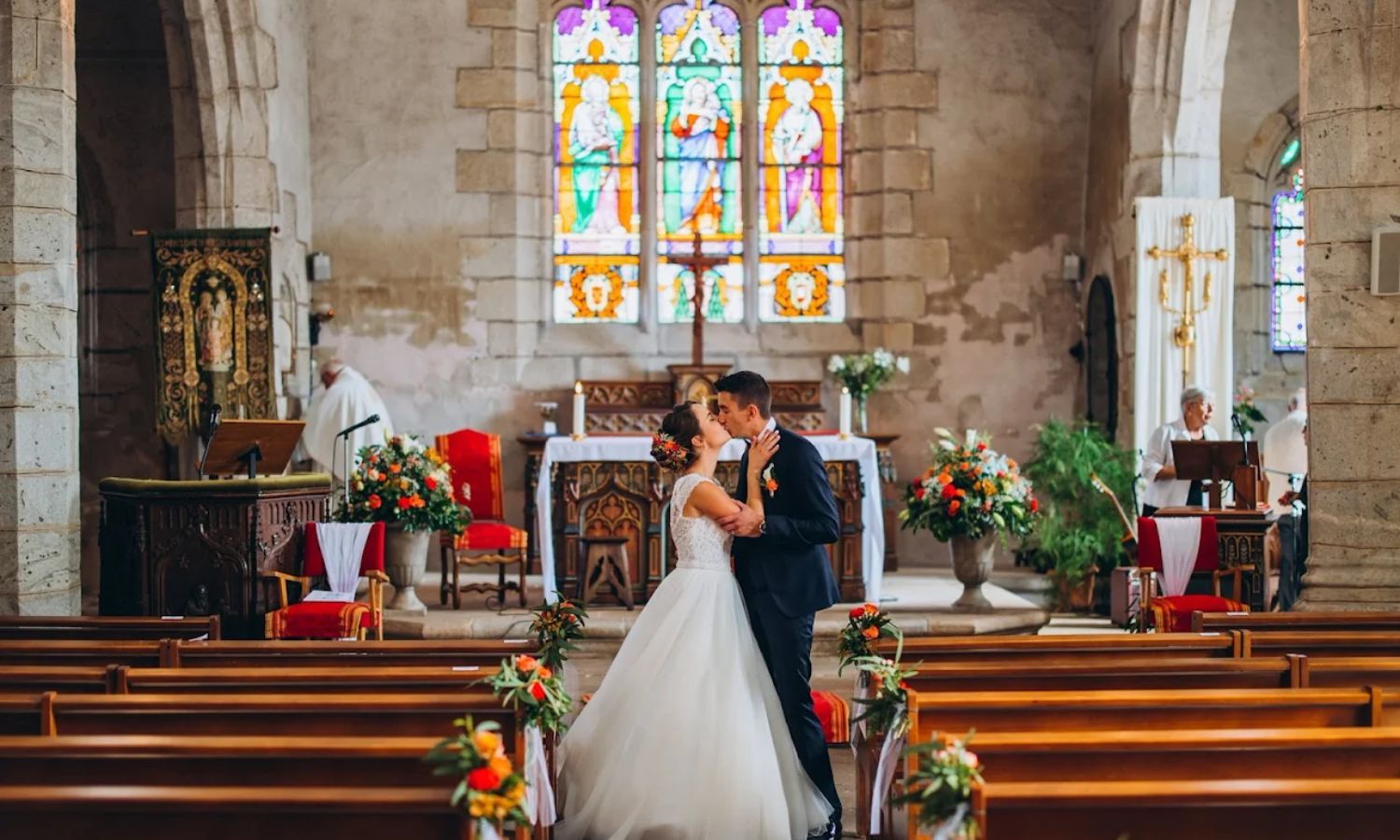 Panoramic view of a traditional church interior with stained glass windows, wooden pews, and floral decorations.