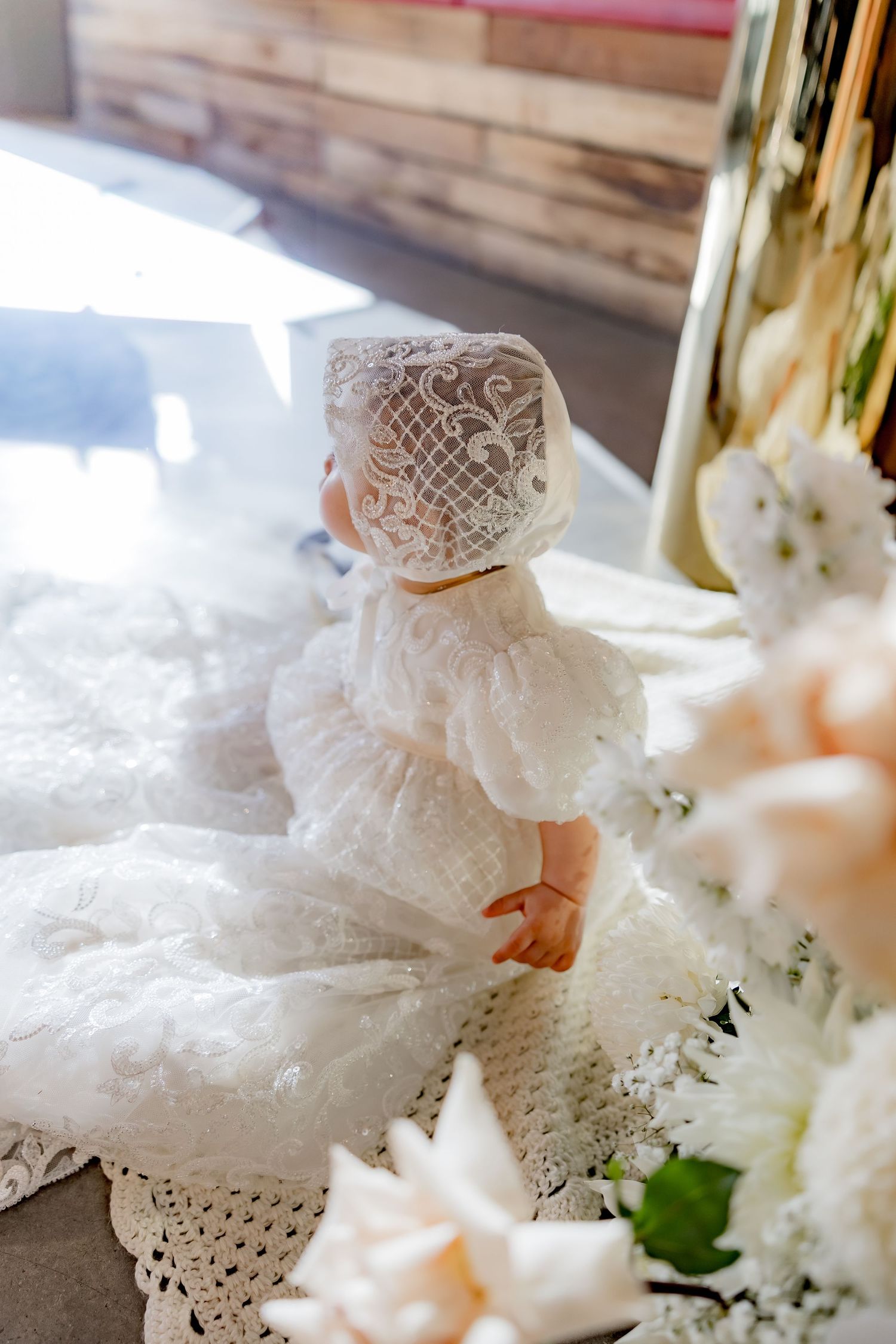A delicate white lace wedding dress detail with intricate floral patterns captured in soft natural lighting.