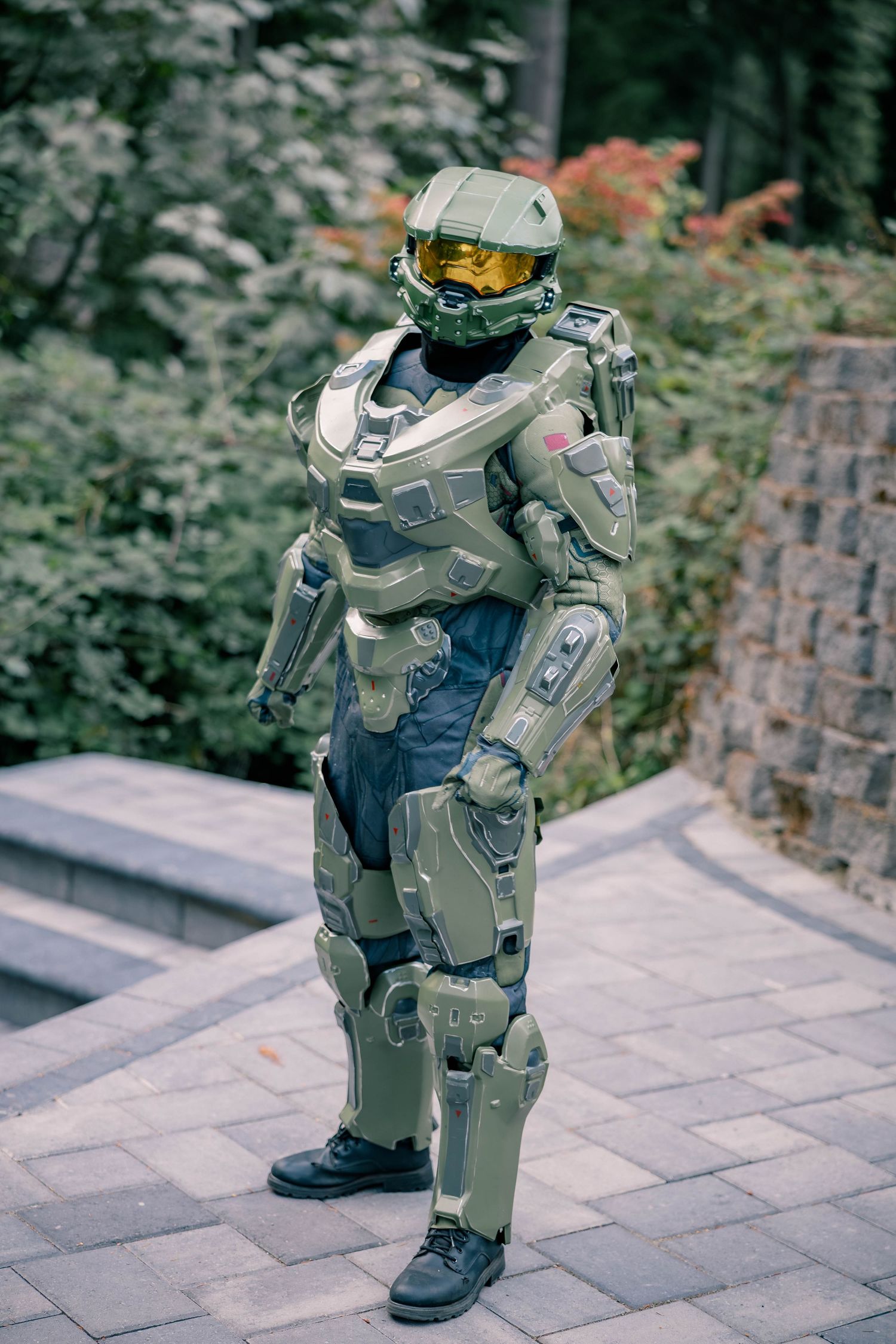 Person wearing a detailed Master Chief Halo cosplay costume standing outdoors on a stone patio.
