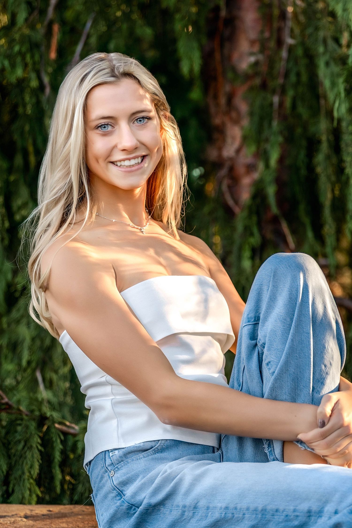 Senior girl hugging her knee wearing jeans and a tub top in Central NY