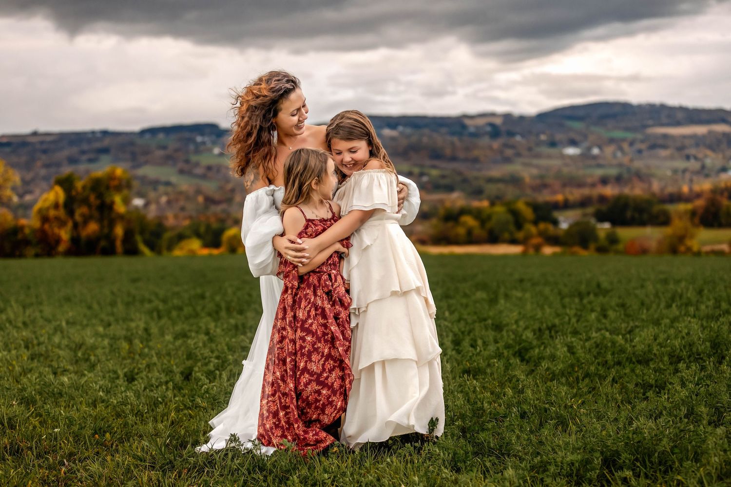 Mother and daughters hugging each other in a field in Central NY