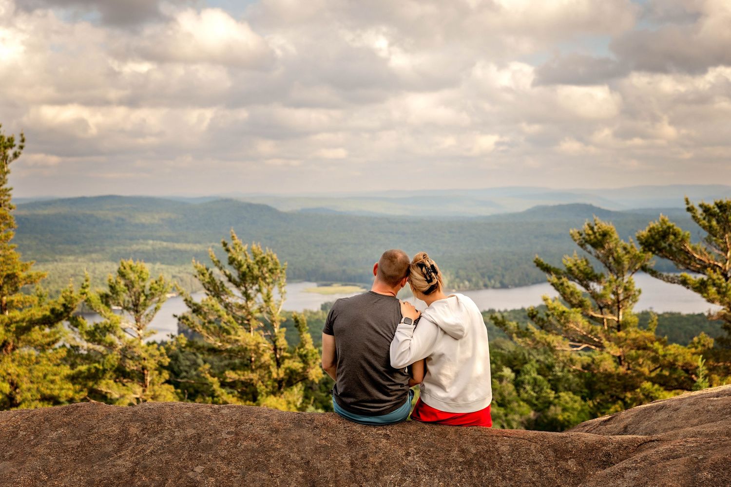 Engagement photos on top of a mountain with the scenic sky and lake in the background in Upstate NY
