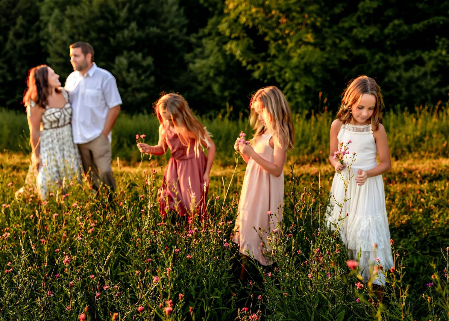 Parents hugging in the background while children pick flowers during golden hour in central NY