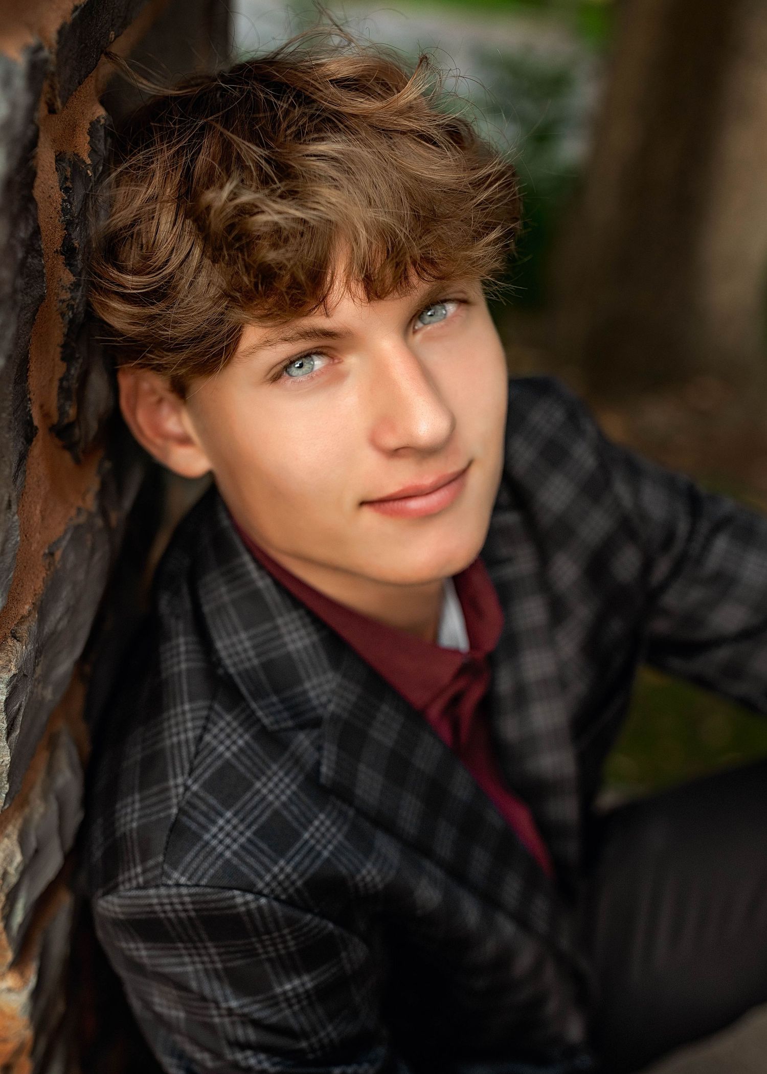 Senior boy in suit leaning against a brick wall in Central NY