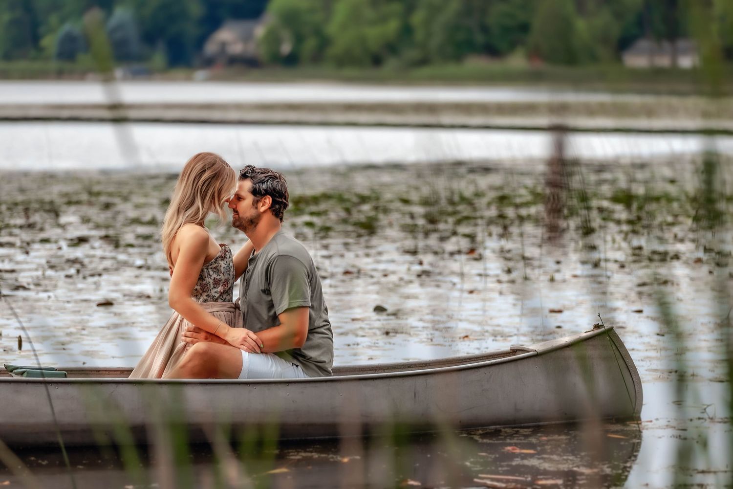 couple in canoe with foreheads touching in the middle of a lake