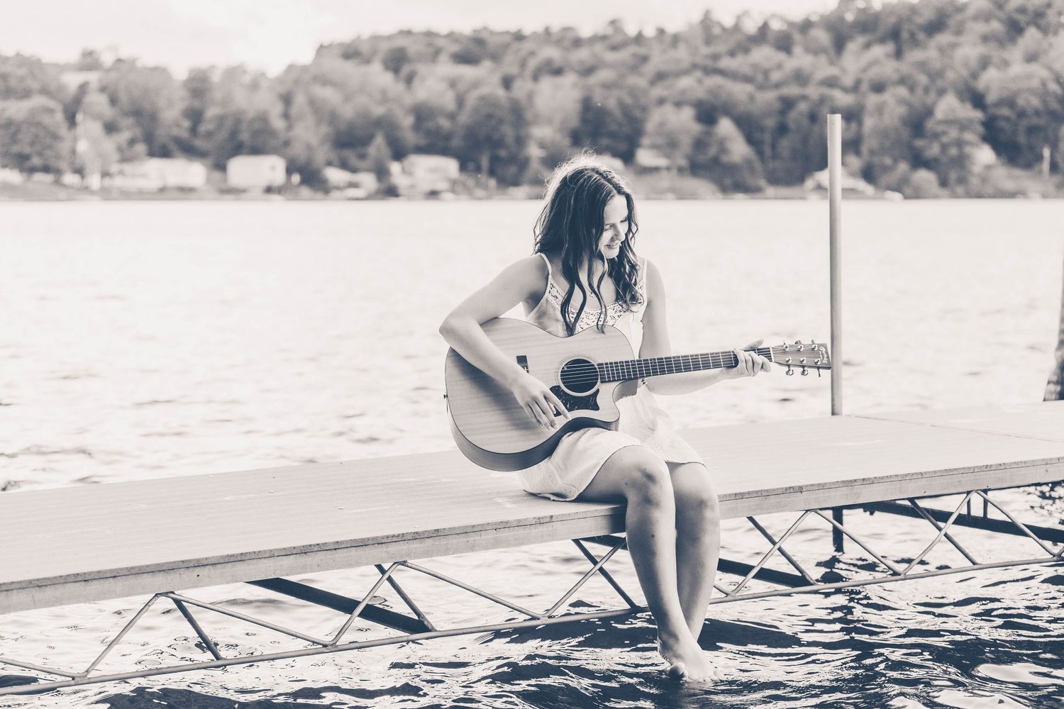 Senior girl sitting on a dock at the lake with a guitar