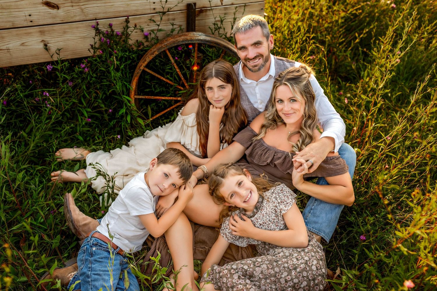 Styled family laying on each other on the ground in front of a wagon in a field in Central NY