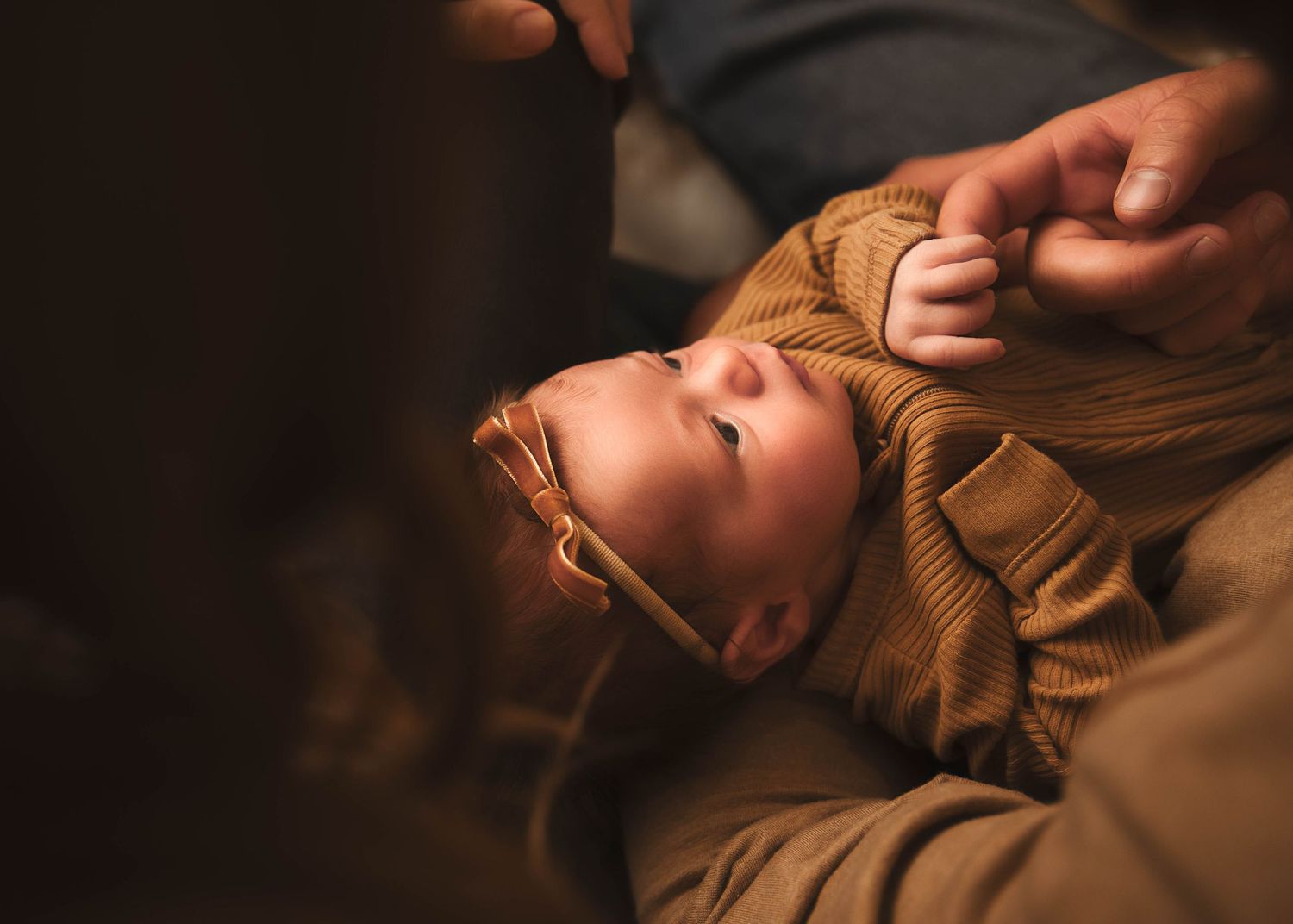 baby girl with her hand wrapped around her dad's finger during lifestyle newborn photos in Central NY