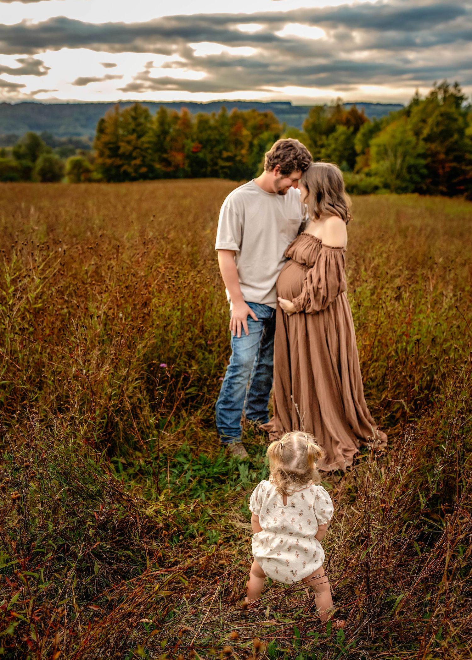 Family maternity photo with parents and toddler in a field in Central NY