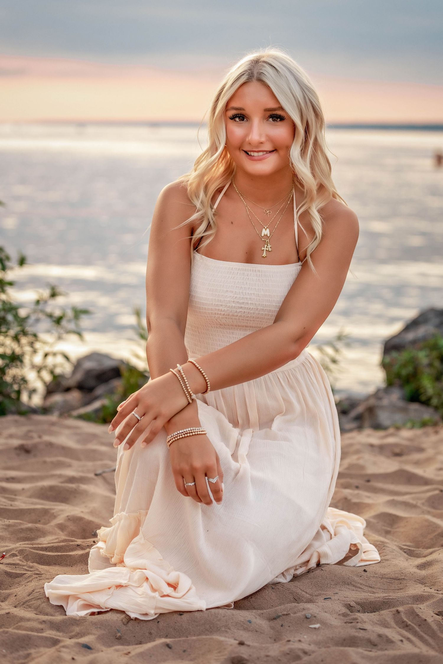 Senior photo on the beach in front of a Oneida Lake at sunset