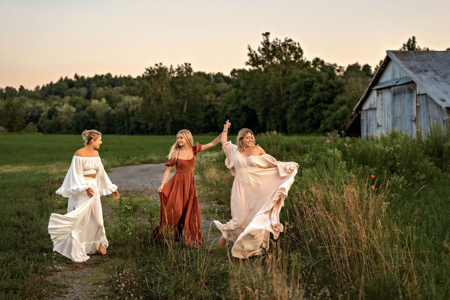 sisters in beautiful dresses holding hands and twirling during golden hour