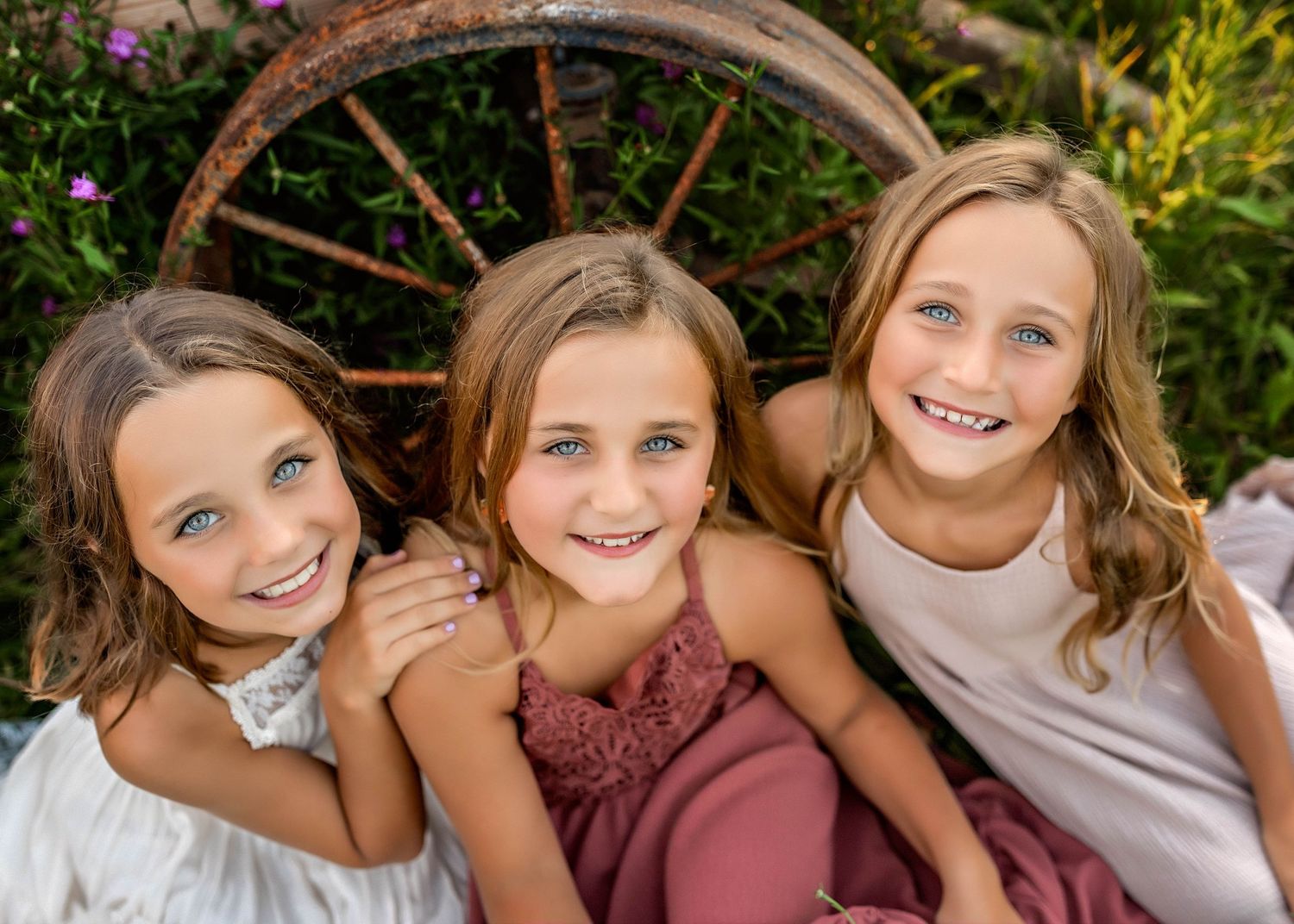 Sisters sitting close together on the ground looking at the camera in Central NY