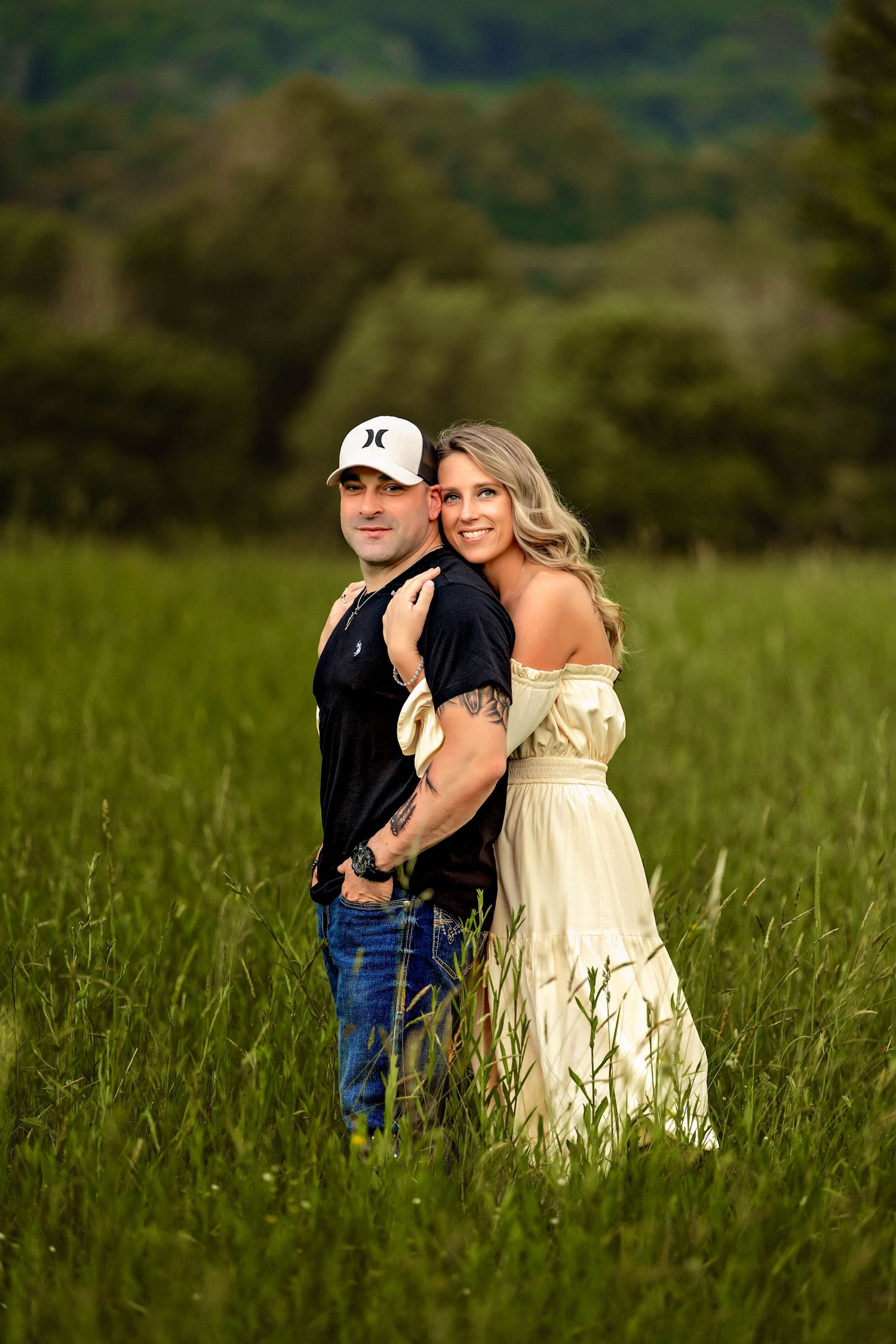 Girl hugging guy from behind with arms wrapped under his during couples photo session in Central NY