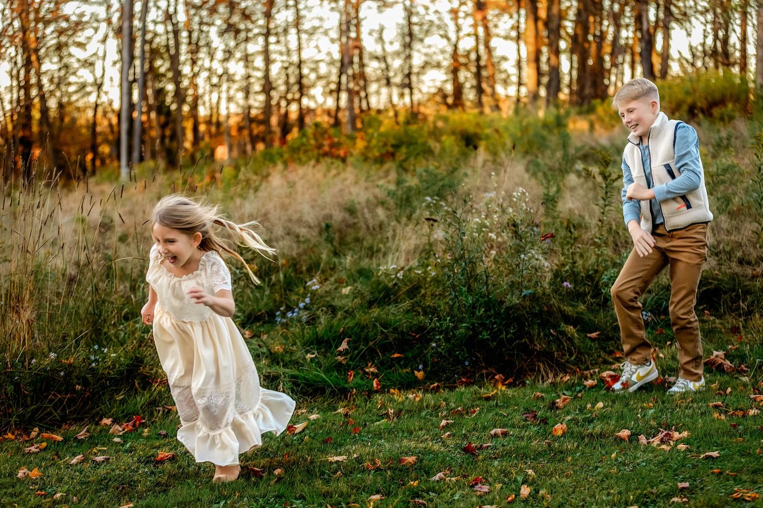 Brother chasing sister and throwing leaves to make her laugh in Central NY