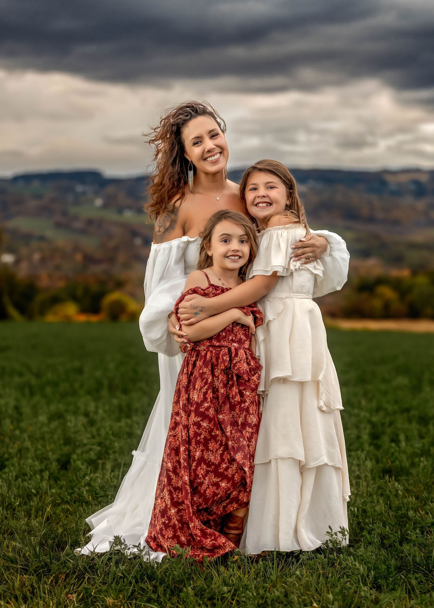 Mother and daughters embracing in a field with a stormy sky
