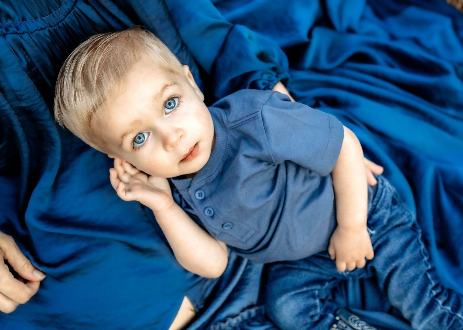 Toddler boy laying on mom's lap looking up at the camera