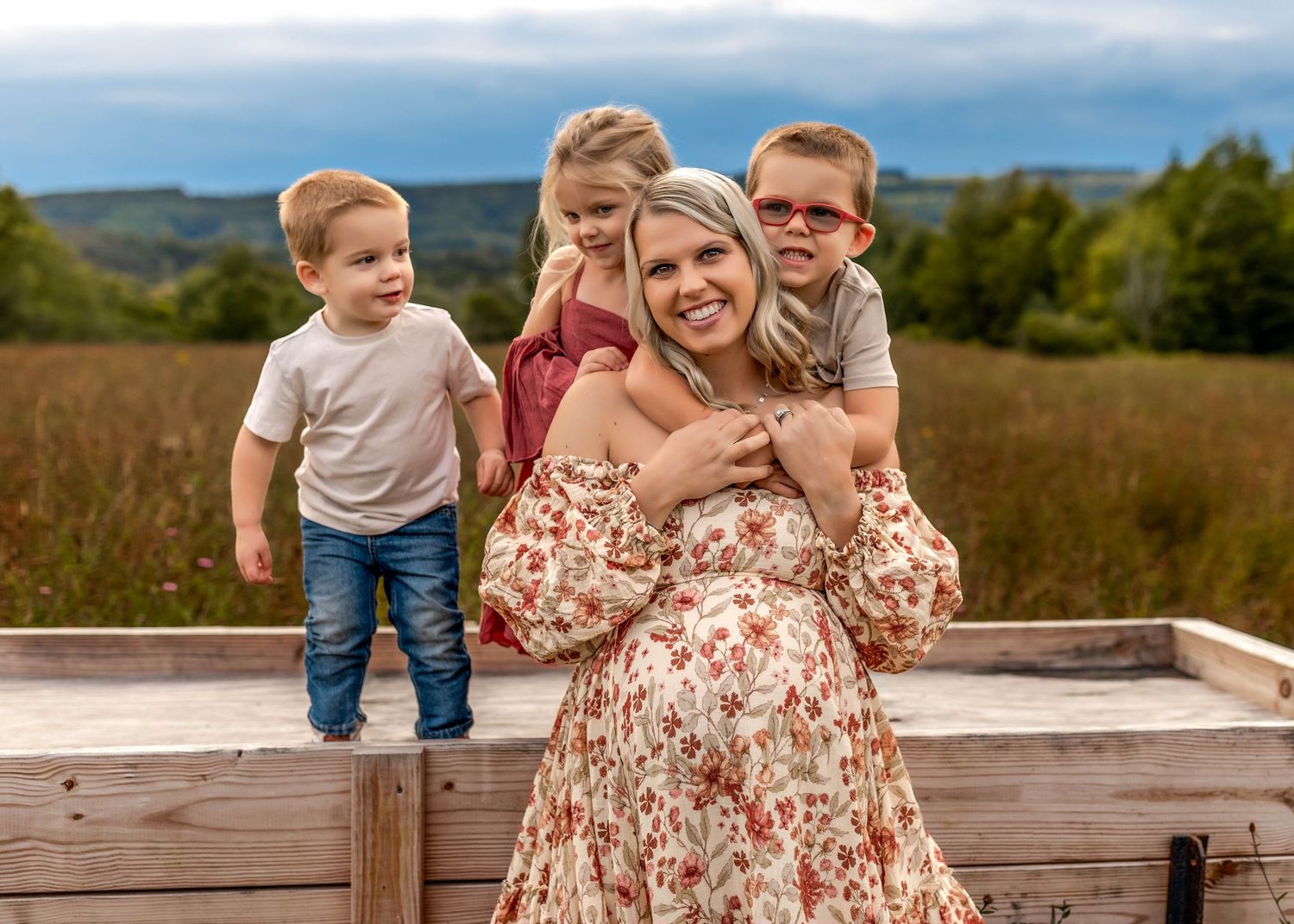Pregnant mother with her children in a field in front of a wagon in Central NY