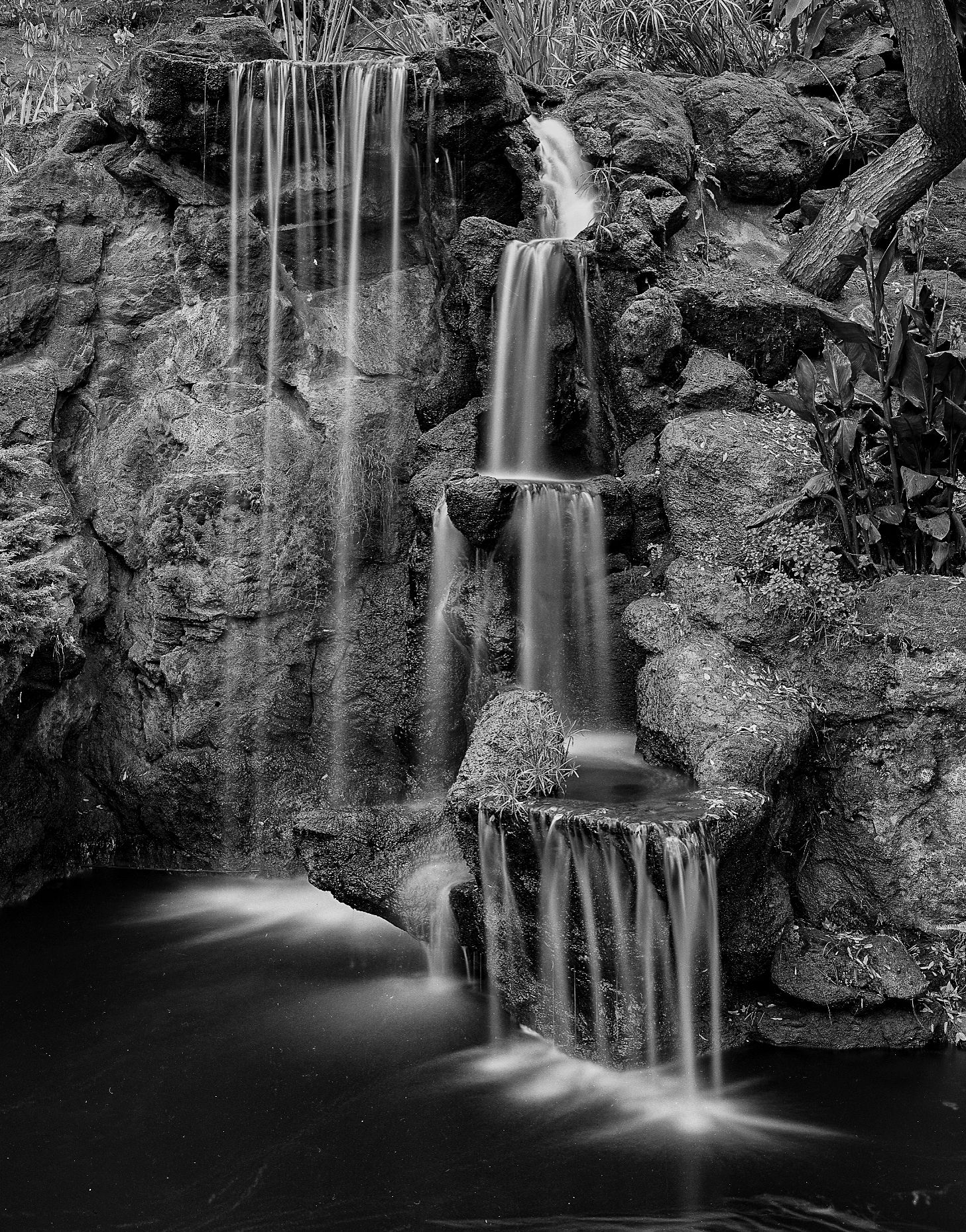 A series of black and white waterfall photographs showing cascading water flowing over rocky cliffs in dramatic long exposures.