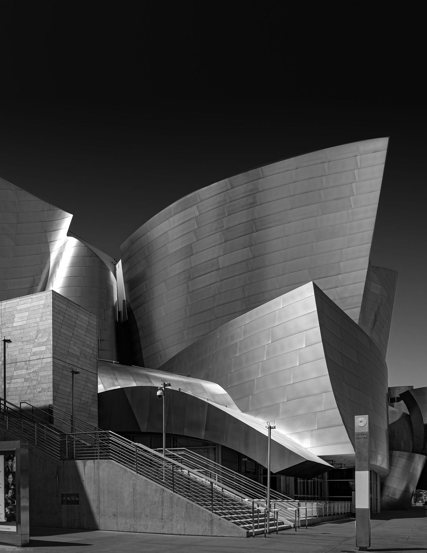 Black and white architectural study of the Walt Disney Concert Hall showing its sweeping metallic curves and geometric forms.