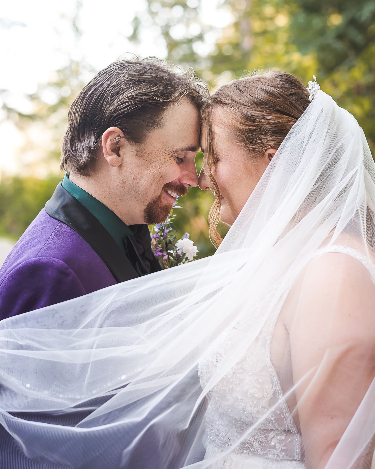 A couple share a moment forehead to forehead during wedding portraits. The bride is wearing a veil. Whonnock Lake, Maple Ridge.