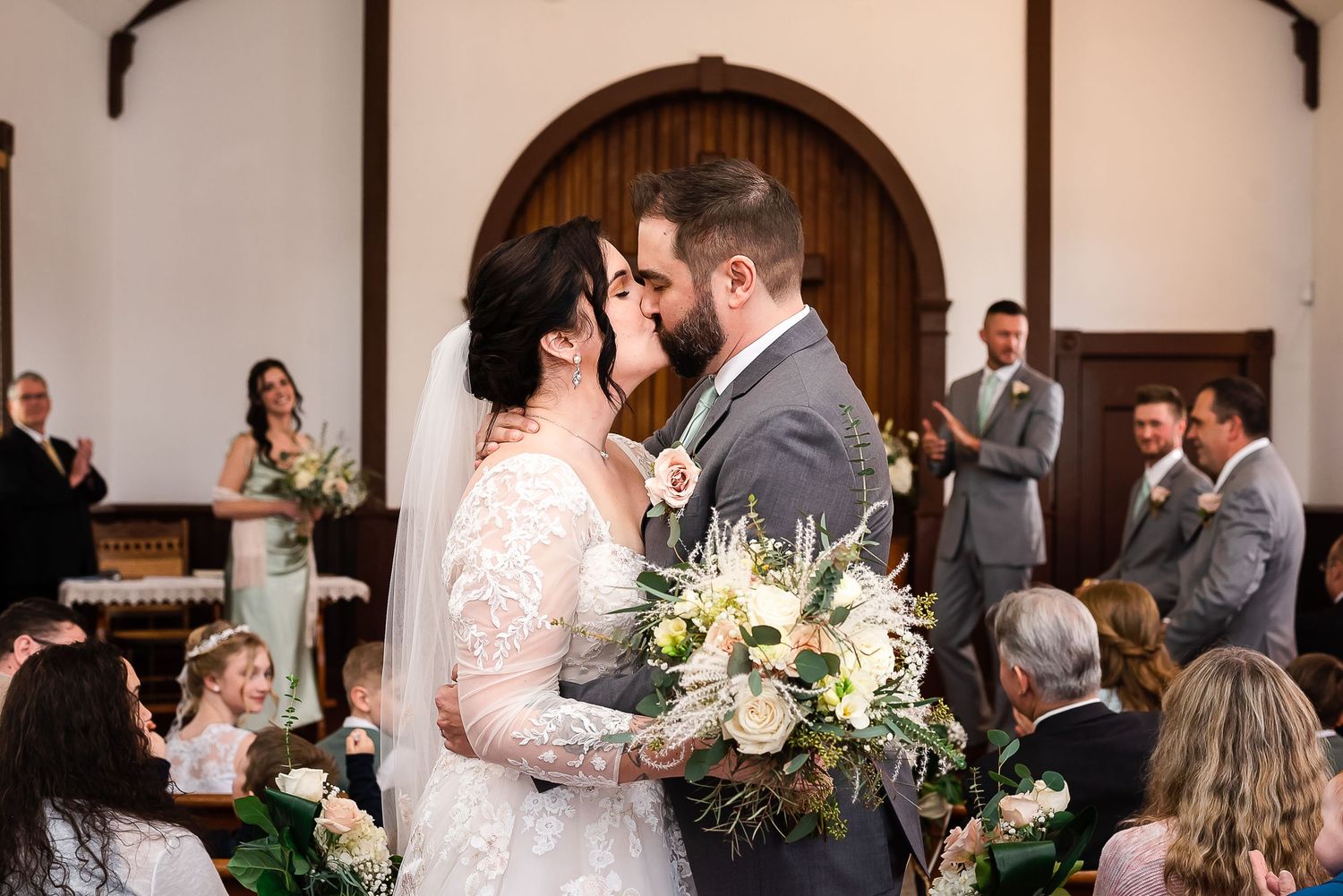 A bride and groom kiss as they walk down the aisle together after their ceremony. Photo taken at Milner Church in Langley, BC by Kari Mills.