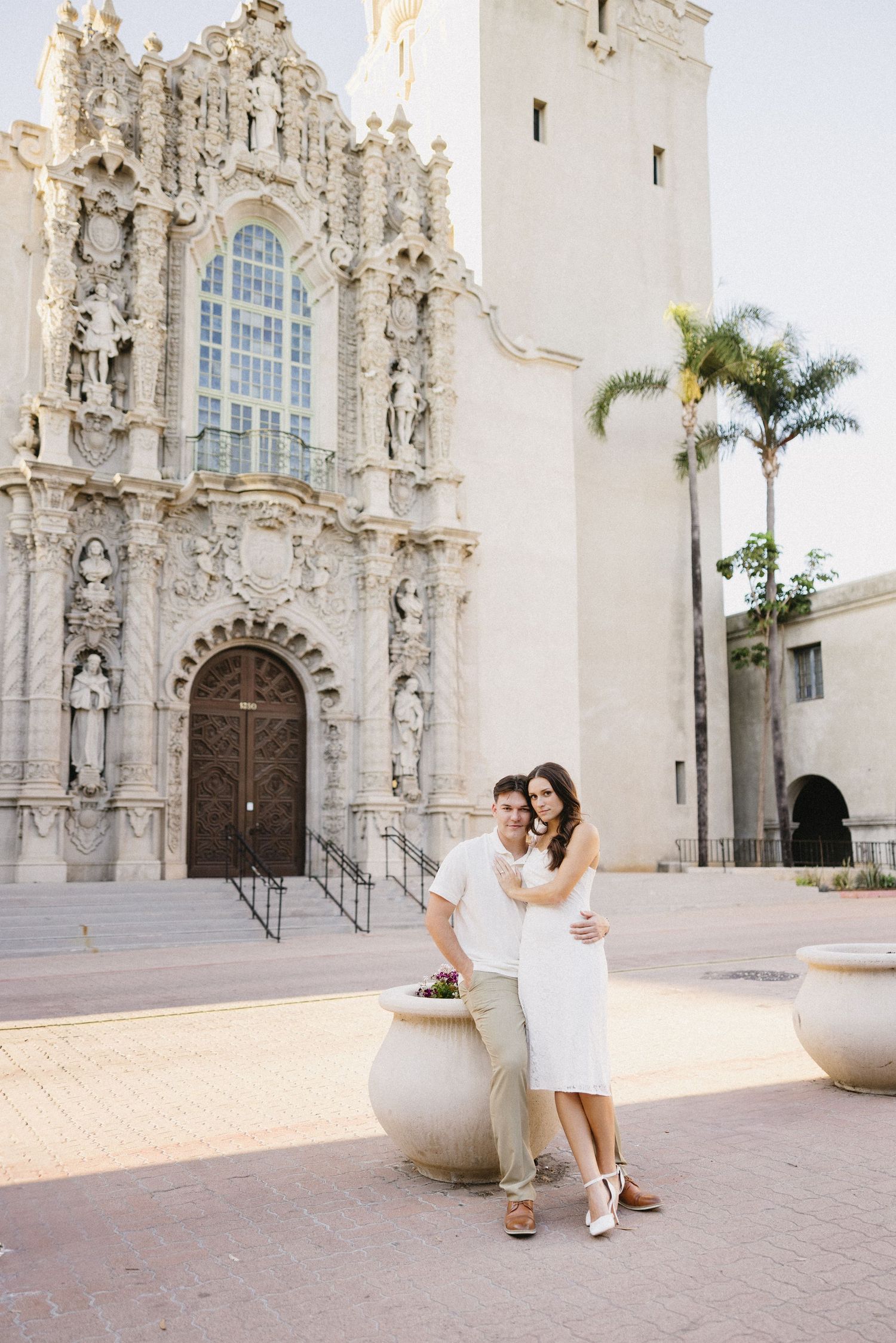 Ornate white Spanish colonial facade with intricate stone carvings and palm trees.