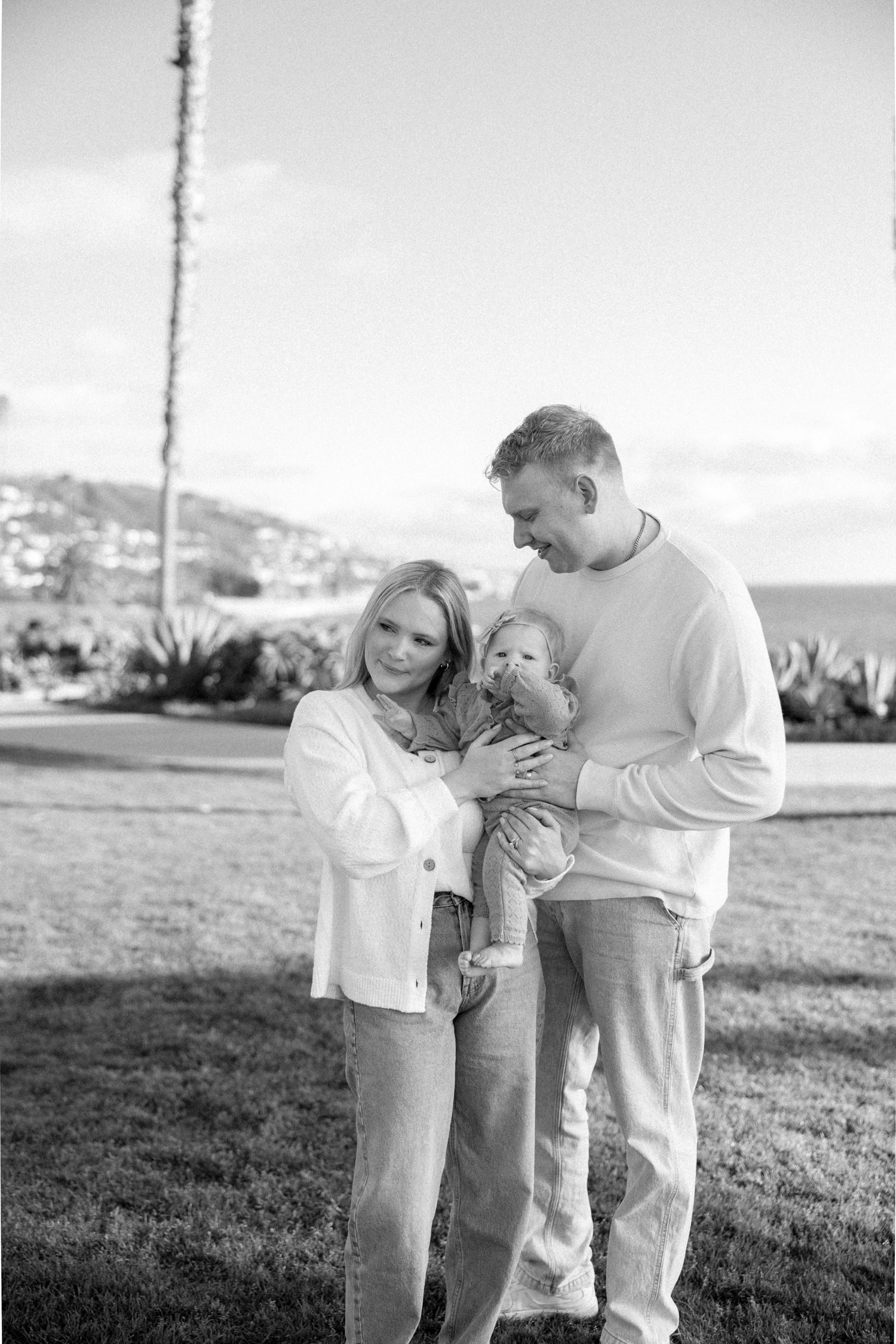 Black and white photo of a family sharing tender moments on a grassy hillside.