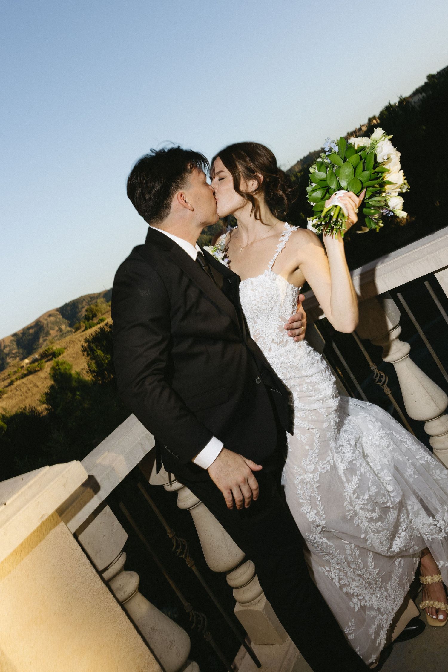 A couple shares a romantic dance at their wedding reception with mountains visible in the background.
