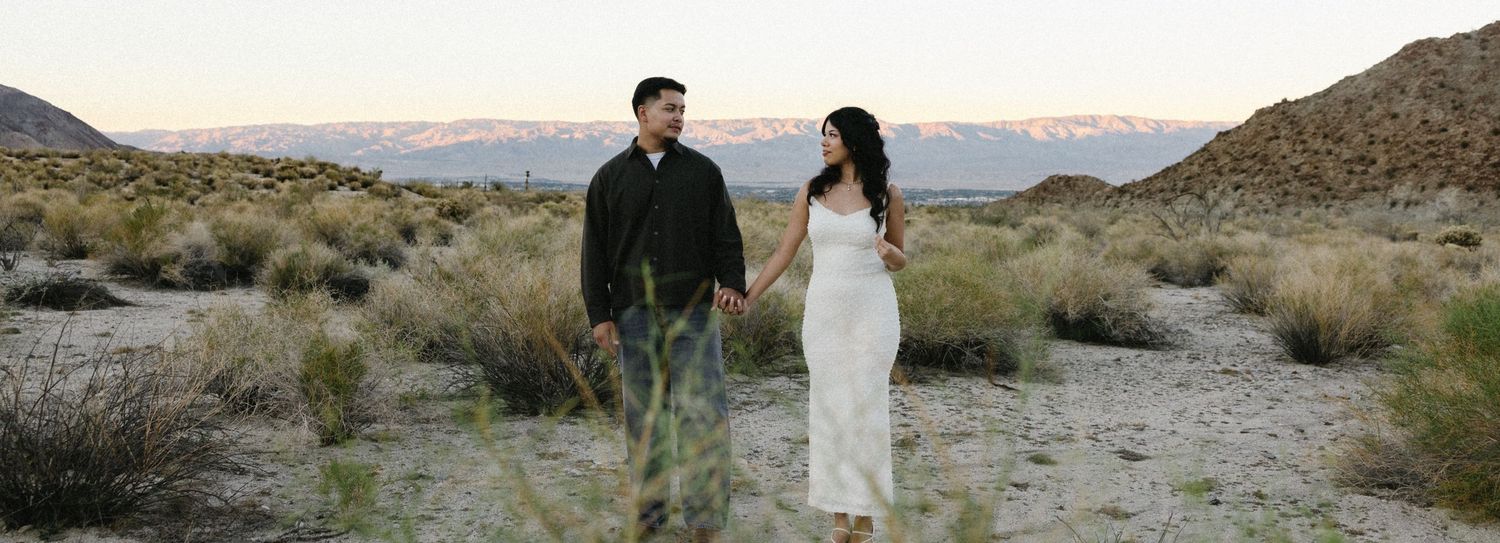 Desert landscape with couple walking in distance against mountain backdrop.