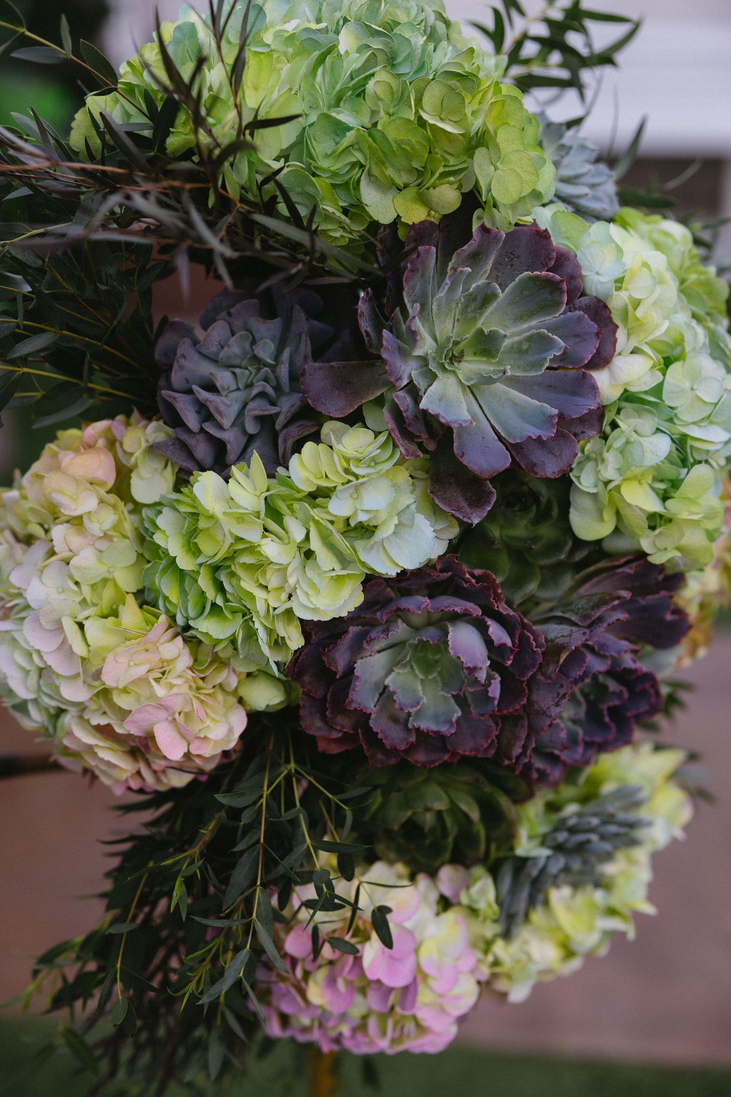 Lush floral bouquet featuring green hydrangeas, purple succulents, and mixed greenery for an elegant arrangement.