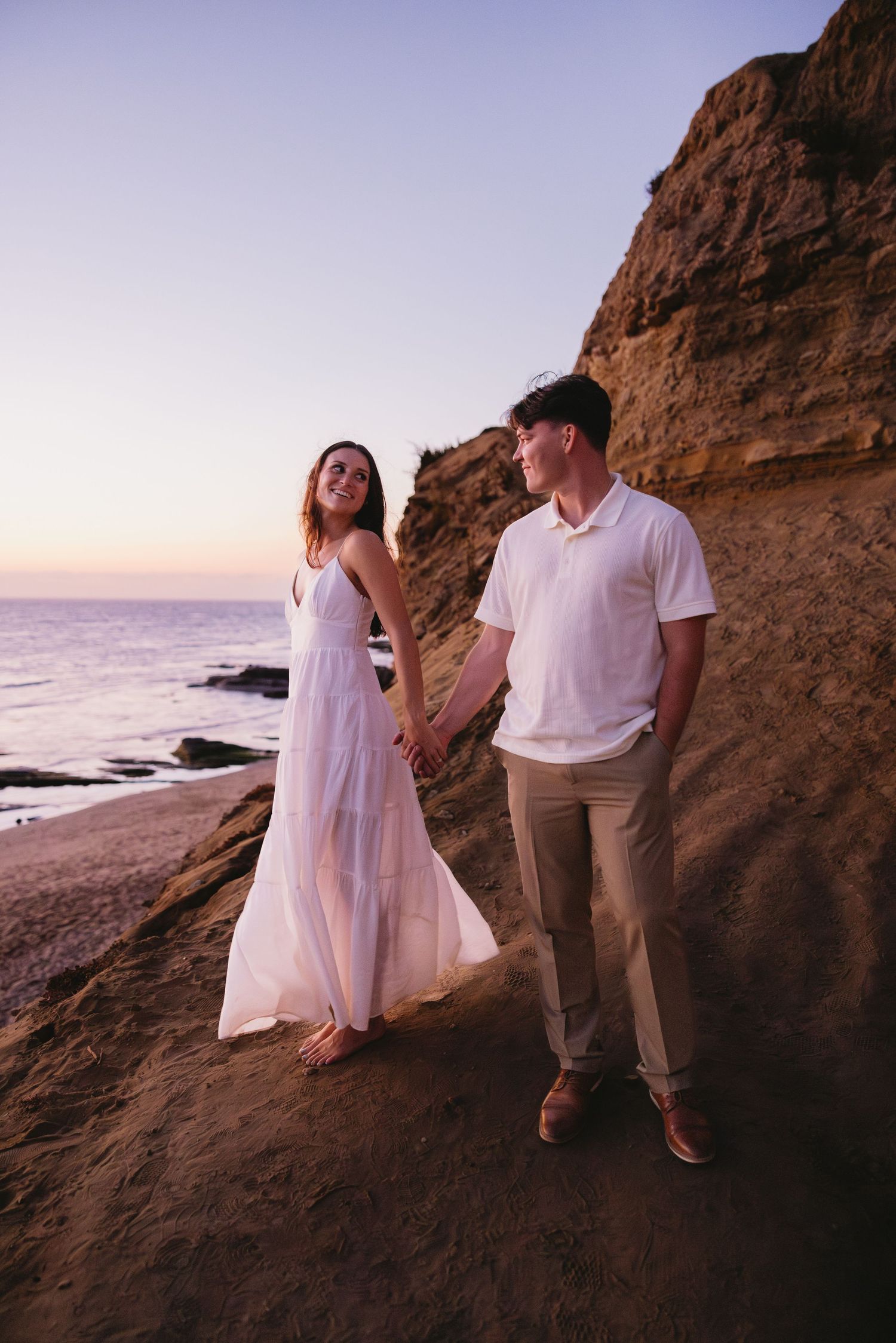 Coastal rock formations and beach at sunset with ocean views.