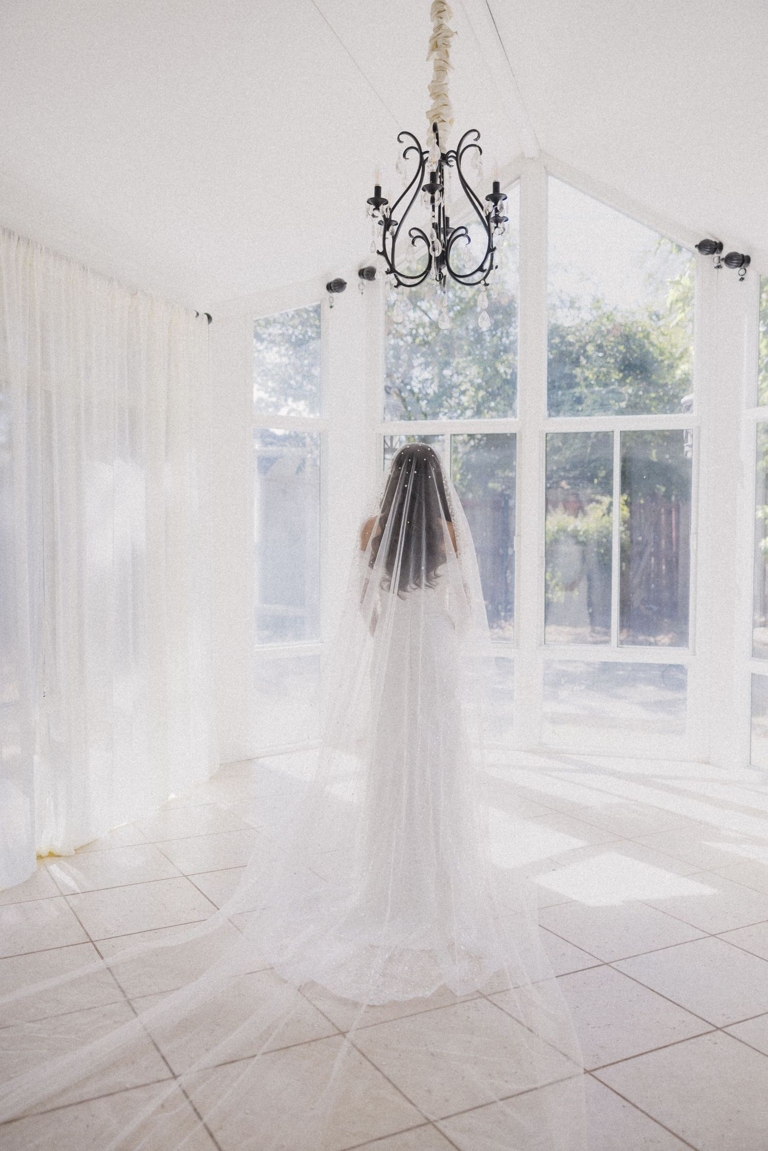 Bright white bridal preparation room with flowing sheer curtains and elegant chandeliers.