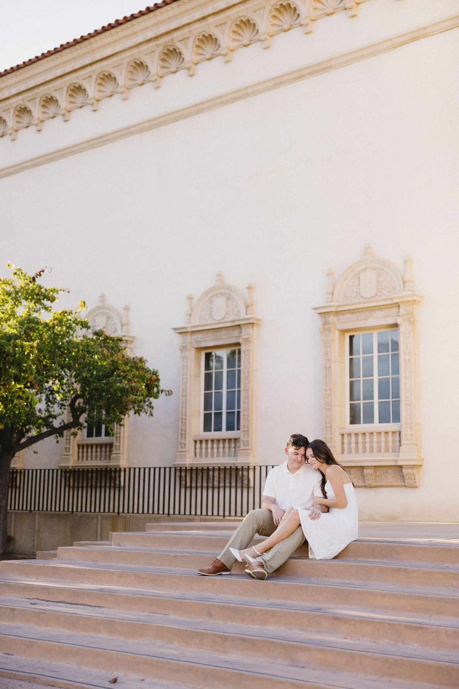 White Spanish colonial building with ornate windows and steps in warm sunlight.