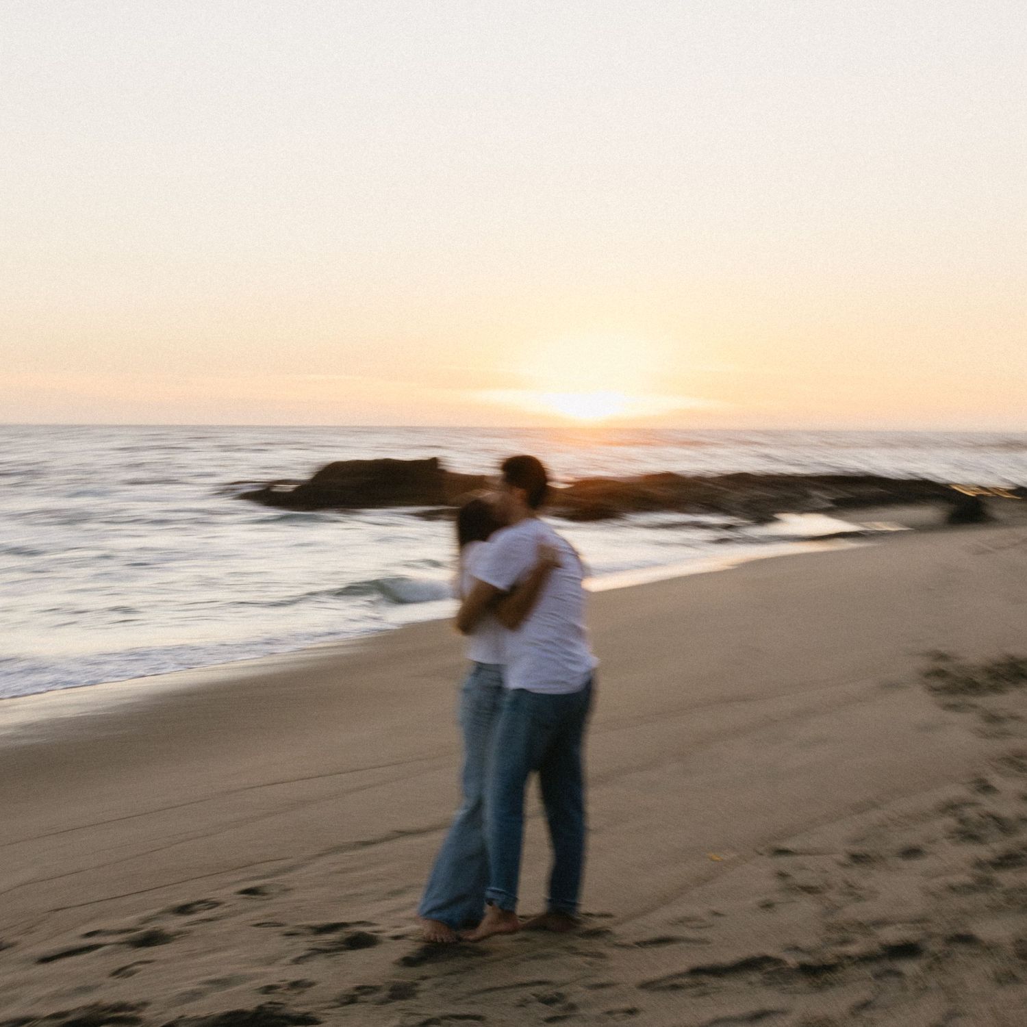Romantic beach photoshoot with couple walking along shoreline at golden hour.