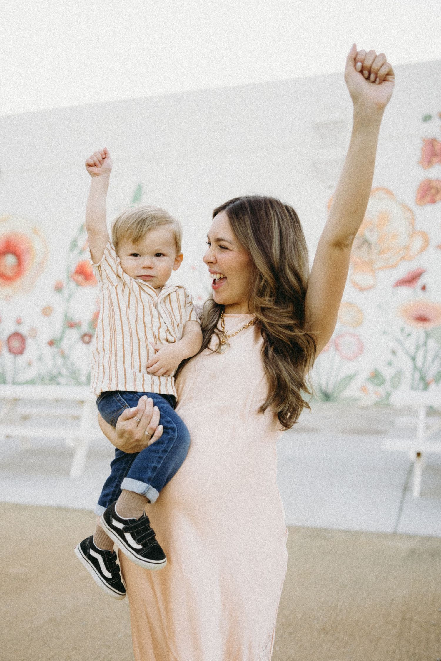 Dancing and celebrating in front of a delicate floral mural backdrop.
