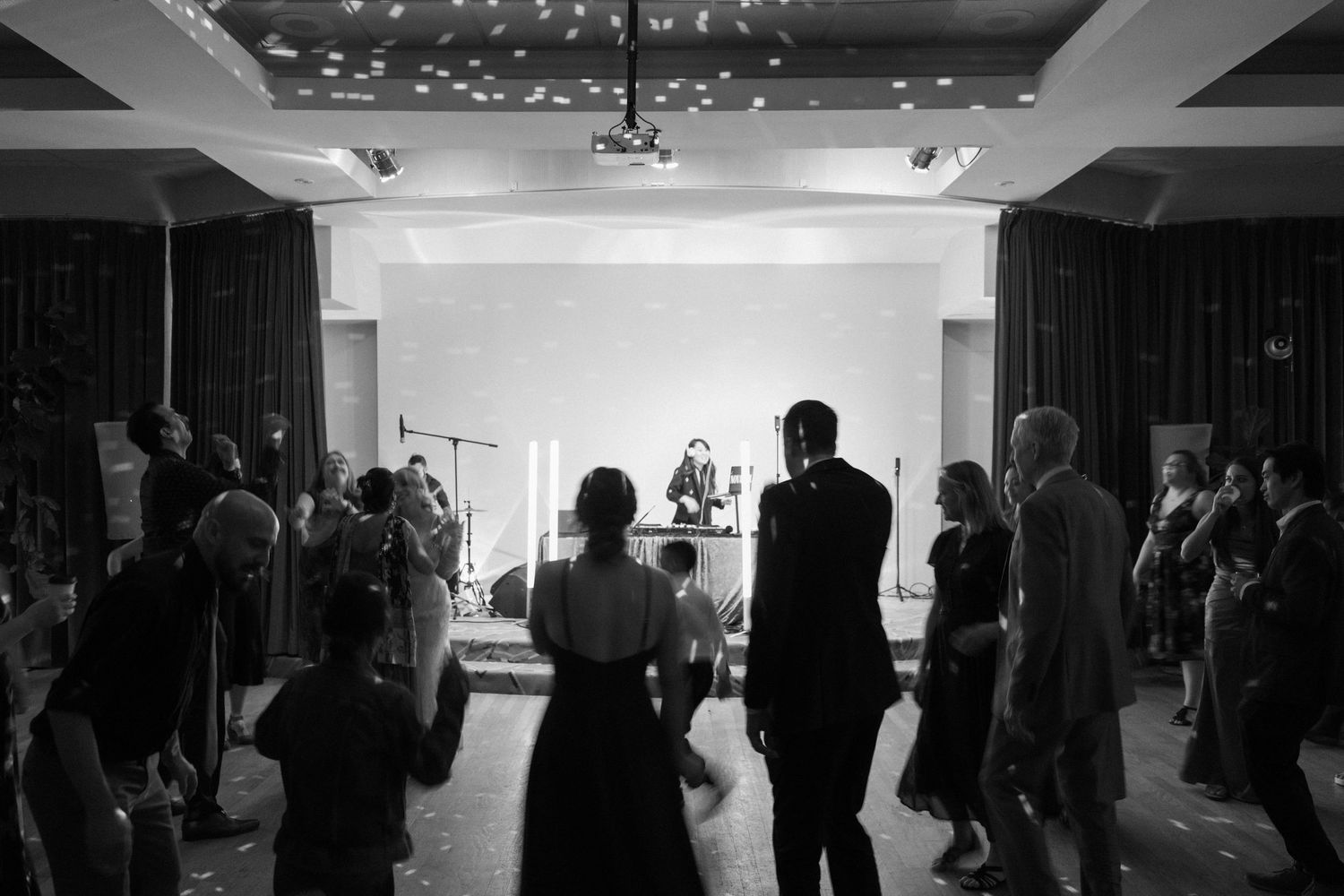 Black and white photo of guests watching a live band perform on stage at an elegant indoor event venue.