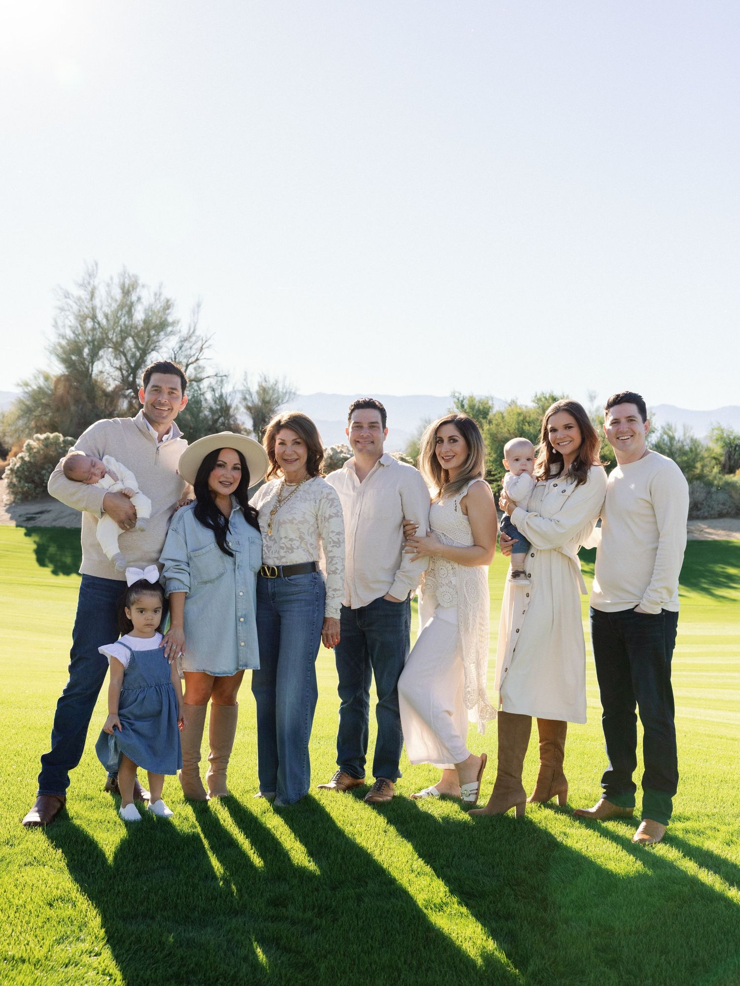 Large family group posing together on grass with coordinated blue and white outfits.