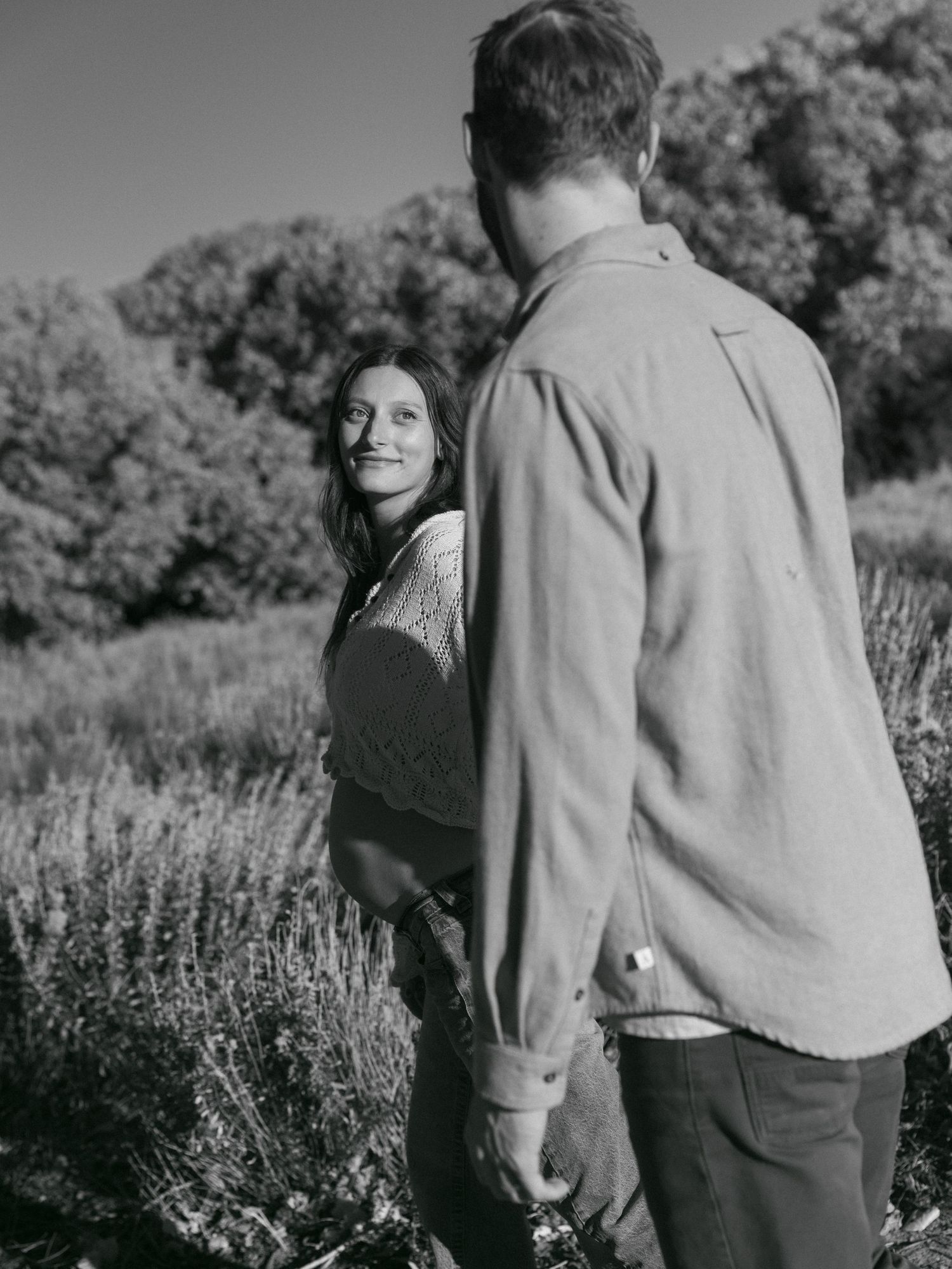 A black and white portrait of a couple in a mountain field with sagebrush.