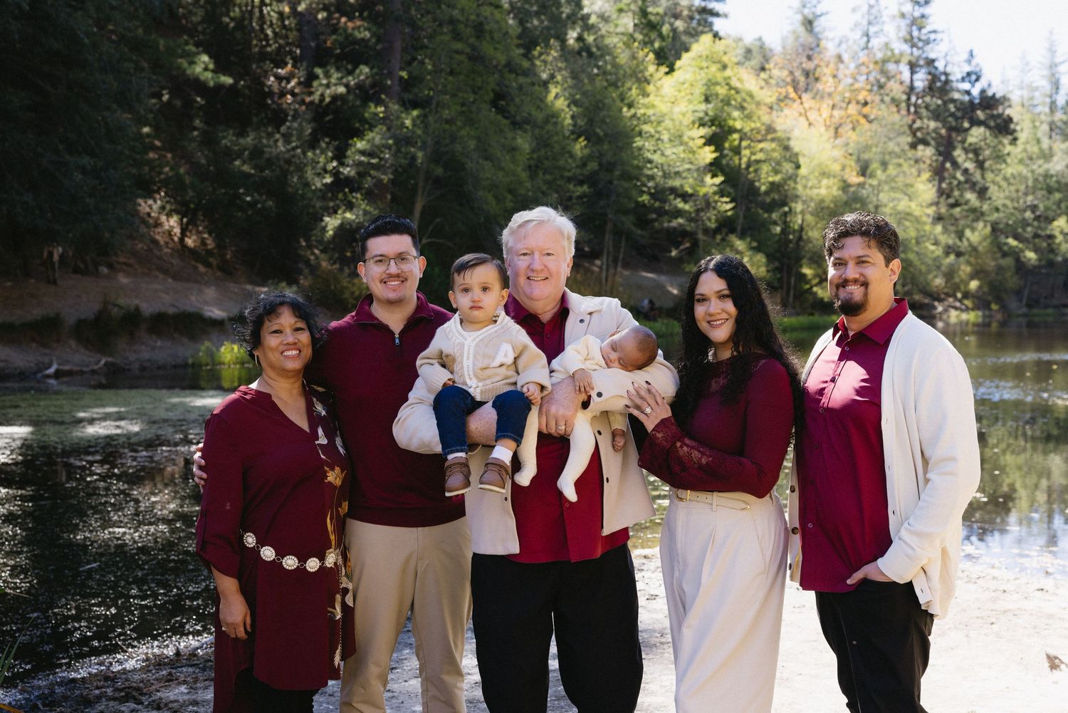 Extended family group photo with members wearing coordinated burgundy and white attire.