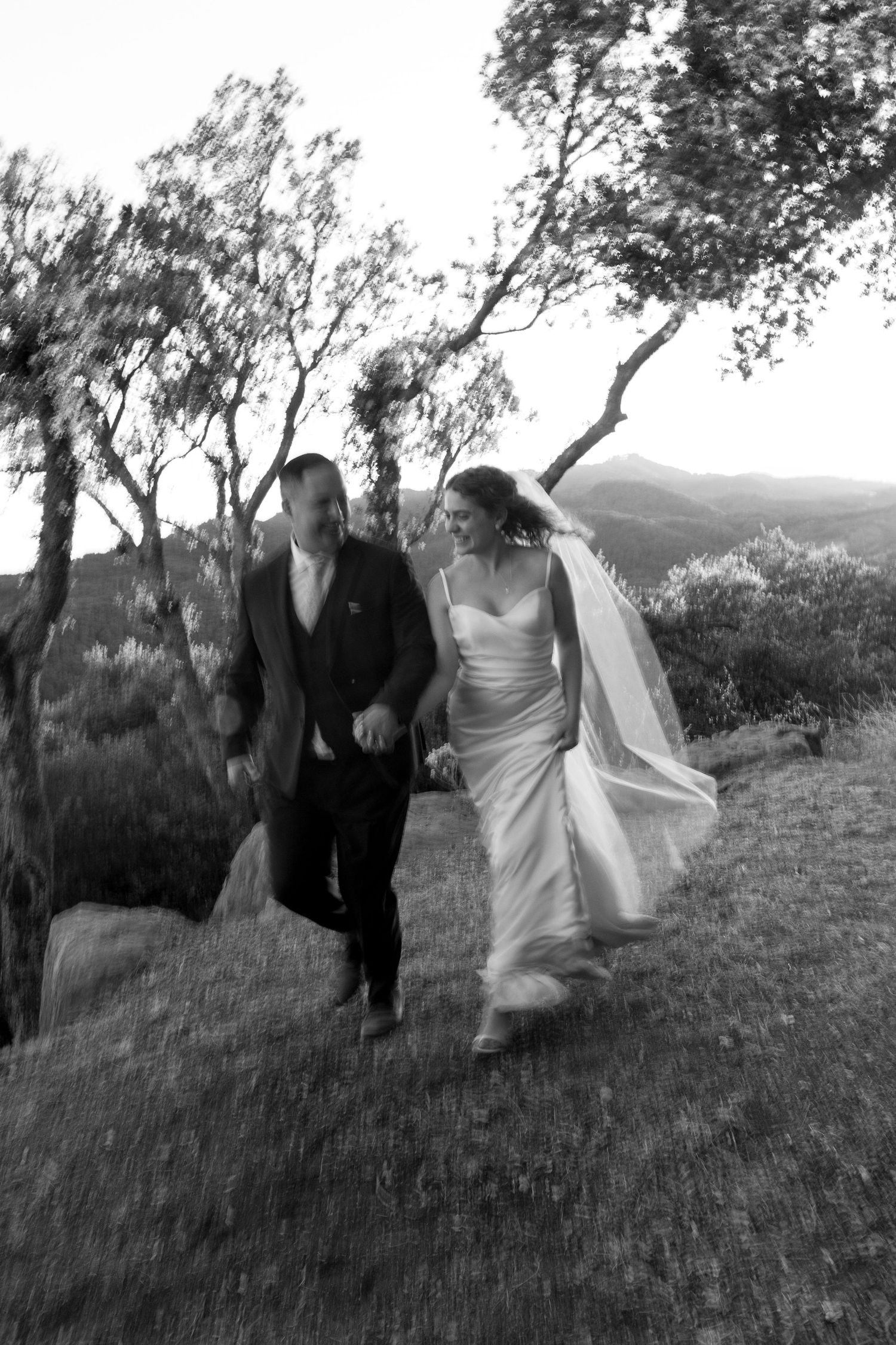 Black and white sequence of a couple running playfully through a grassy hillside landscape.