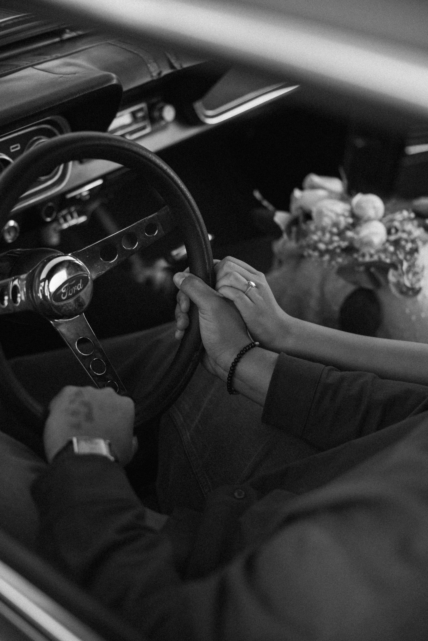 Interior view of vintage car dashboard and steering wheel in black and white.